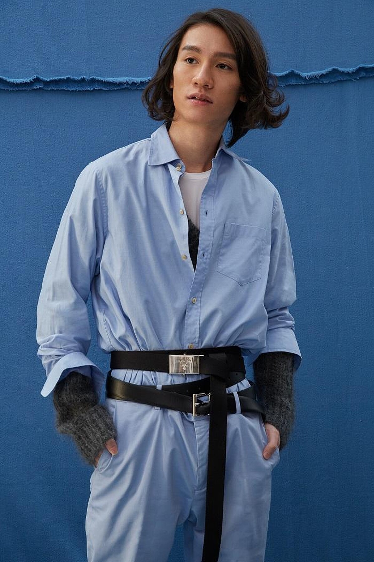  粉藍襯衫 by GUCCI ；水藍長褲 by GIEVES & HAWKES；灰針織毛衣、梭織雙圈腰帶、雙圈皮腰帶、造型皮鞋All by PRADA。