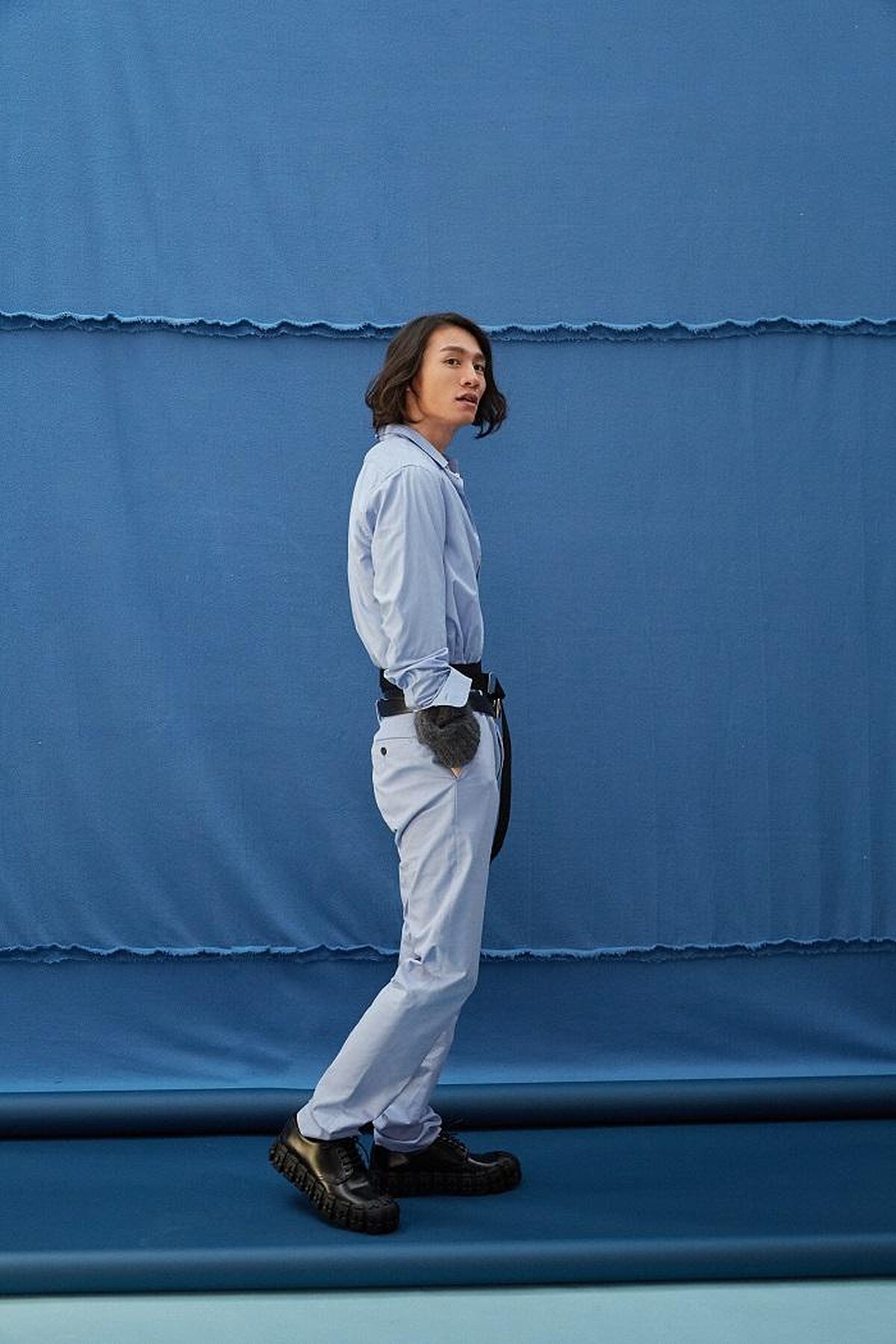  粉藍襯衫 by GUCCI ；水藍長褲 by GIEVES & HAWKES；灰針織毛衣、梭織雙圈腰帶、雙圈皮腰帶、造型皮鞋All by PRADA。