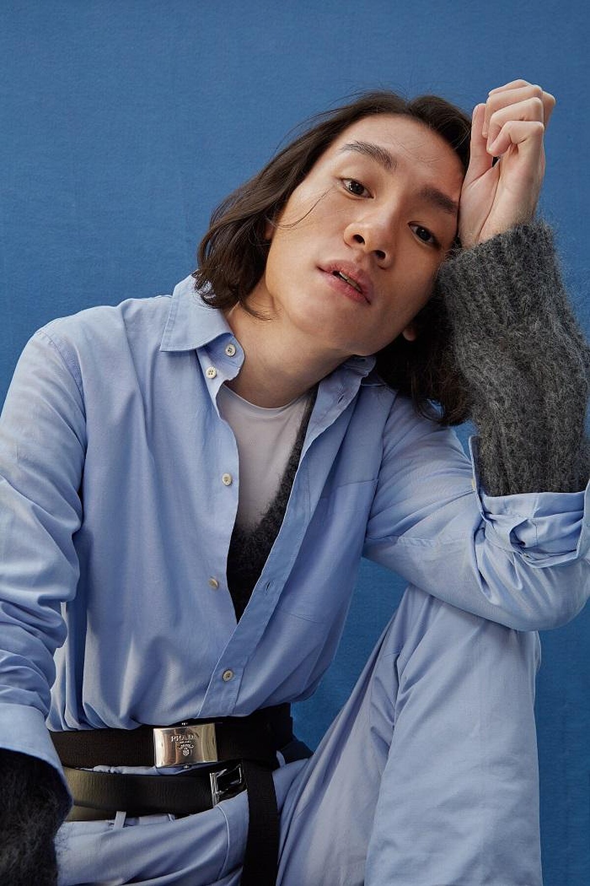  粉藍襯衫 by GUCCI ；水藍長褲 by GIEVES & HAWKES；灰針織毛衣、梭織雙圈腰帶、雙圈皮腰帶、造型皮鞋All by PRADA。