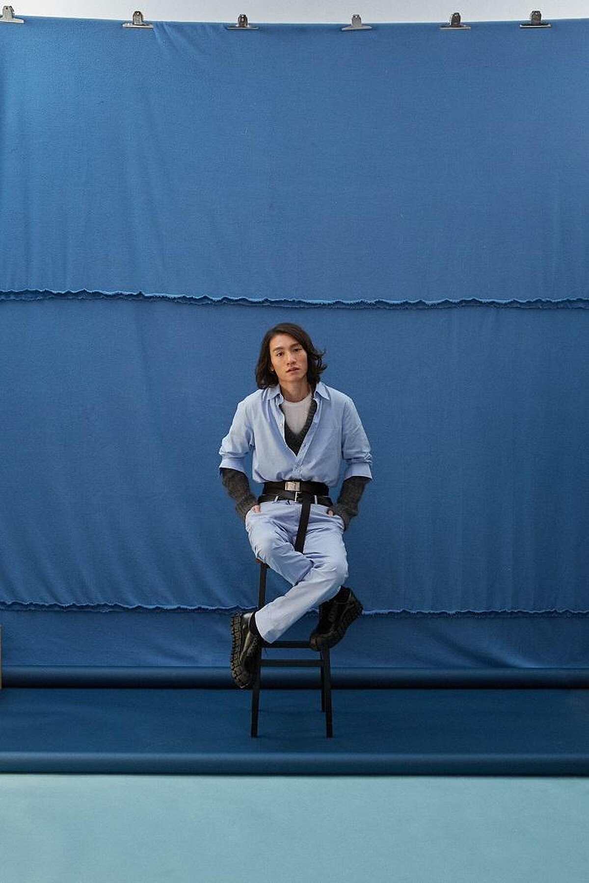  粉藍襯衫 by GUCCI ；水藍長褲 by GIEVES & HAWKES；灰針織毛衣、梭織雙圈腰帶、雙圈皮腰帶、造型皮鞋All by PRADA。