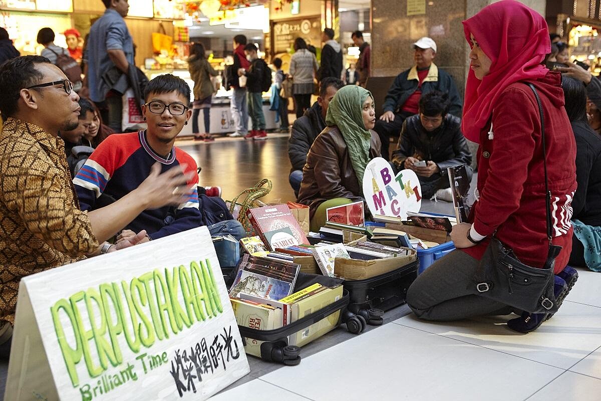 移工作家 Justto Lasoo 及燦爛時光策展人吳庭寬和來借書的移工朋友聊天。