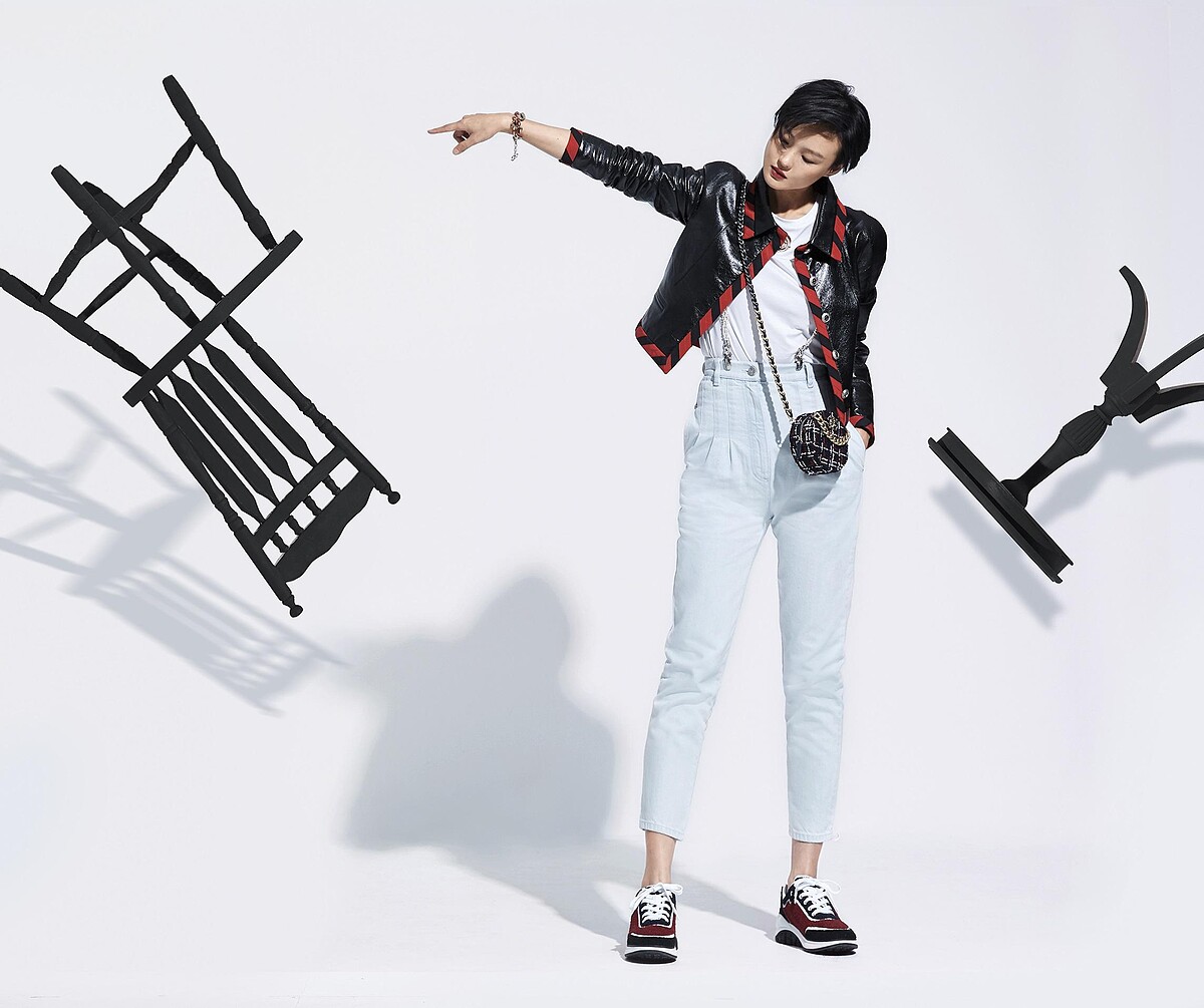 紅黑格紋斜紋軟呢CHANEL 19圓形小包、黑色小羊皮外套、白色T恤、紅色金屬小牛皮手鍊、珍珠吊帶、水洗牛仔褲、運動鞋；All by CHANEL。