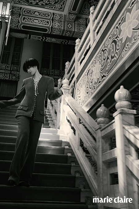 珍珠長串鍊、赤朱色斜紋軟昵外套、赤朱色斜紋軟昵長褲、包頭高跟鞋，all by Chanel。