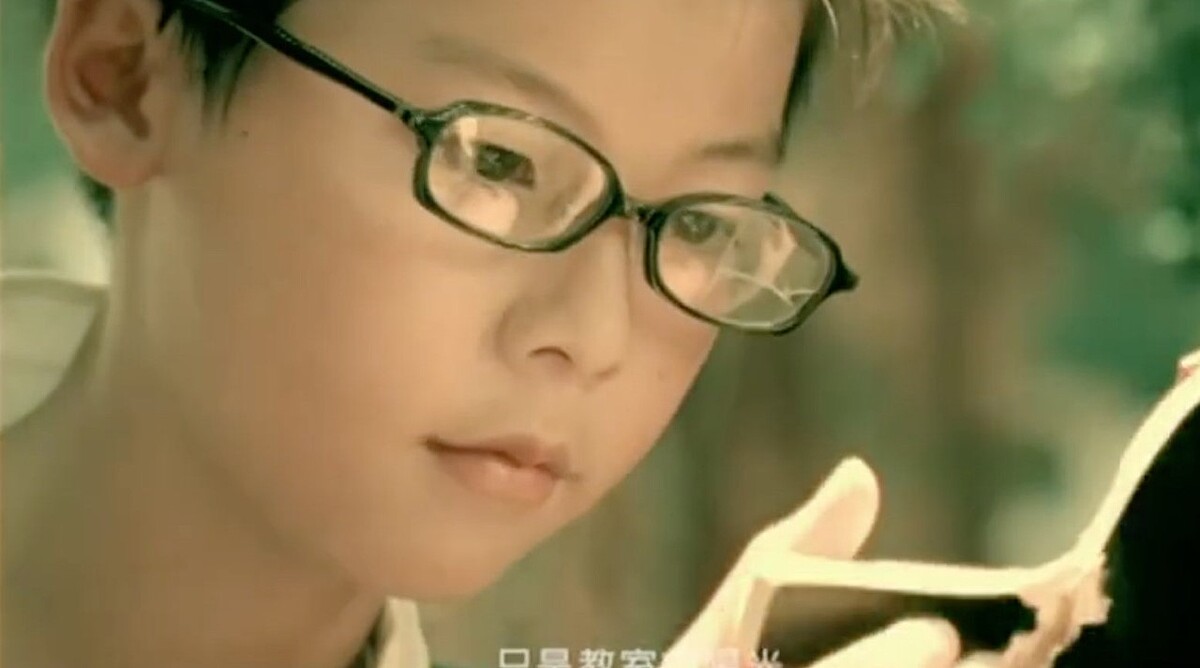 帶著細框眼鏡的桌球隊小隊員正是許光漢本人，乾淨的五官直到今天仍舊沒有絲毫的改變。 Photo / YouTube 周杰倫《三年二班》畫面）