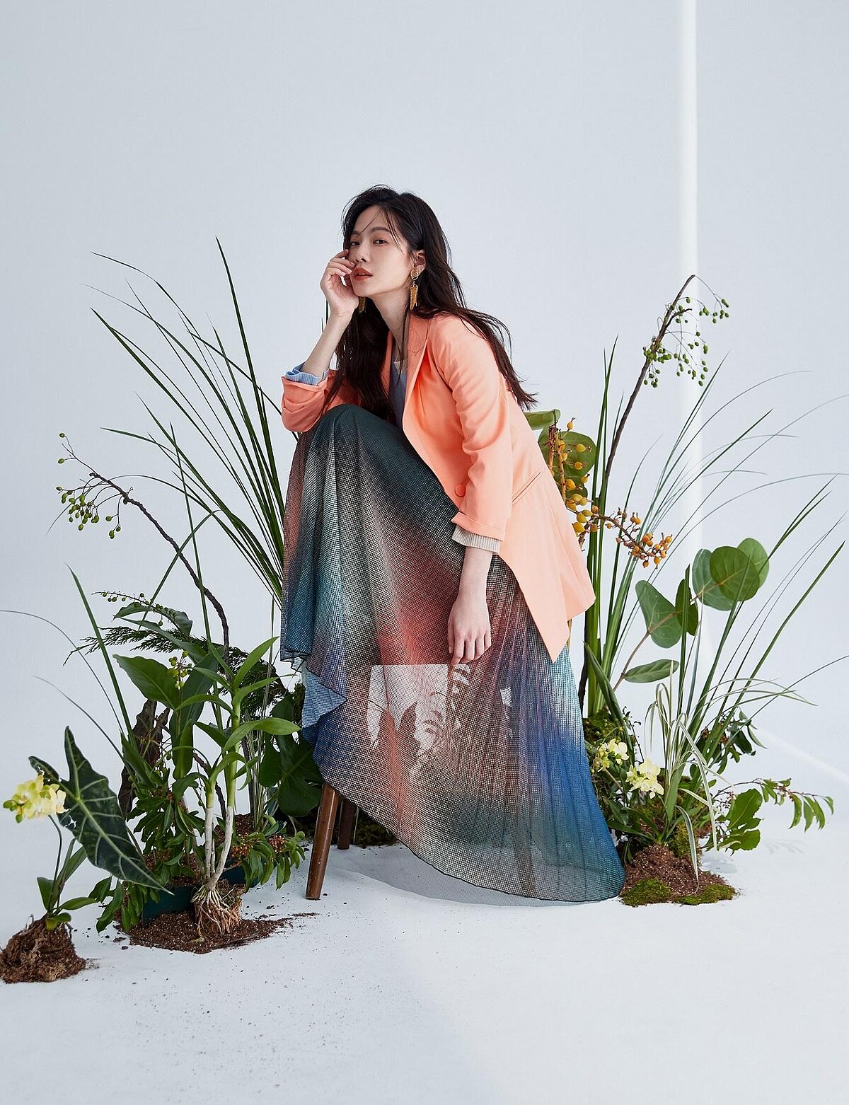 身穿粉橘色套裝與唯美漸層百褶裙，有如在一片綠意盎然中翩然起舞般夢幻。