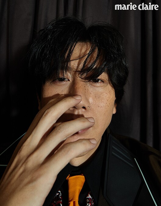 黑色襯衫、明黃領帶、鉤織混紡毛衣、咖啡色尼龍長版風衣、黑長褲、厚底紳士鞋，all by Prada。