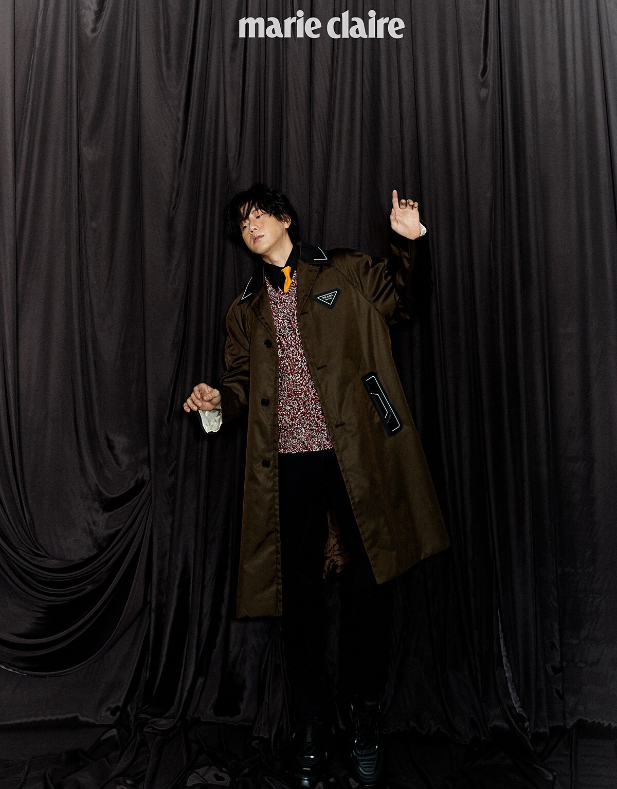 黑色襯衫、明黃領帶、鉤織混紡毛衣、咖啡色尼龍長版風衣、黑長褲、厚底紳士鞋，all by Prada。