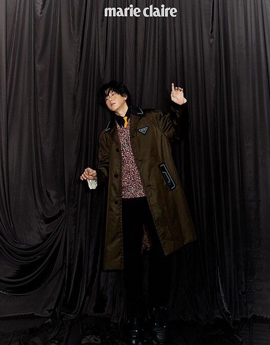 黑色襯衫、明黃領帶、鉤織混紡毛衣、咖啡色尼龍長版風衣、黑長褲、厚底紳士鞋，all by Prada。