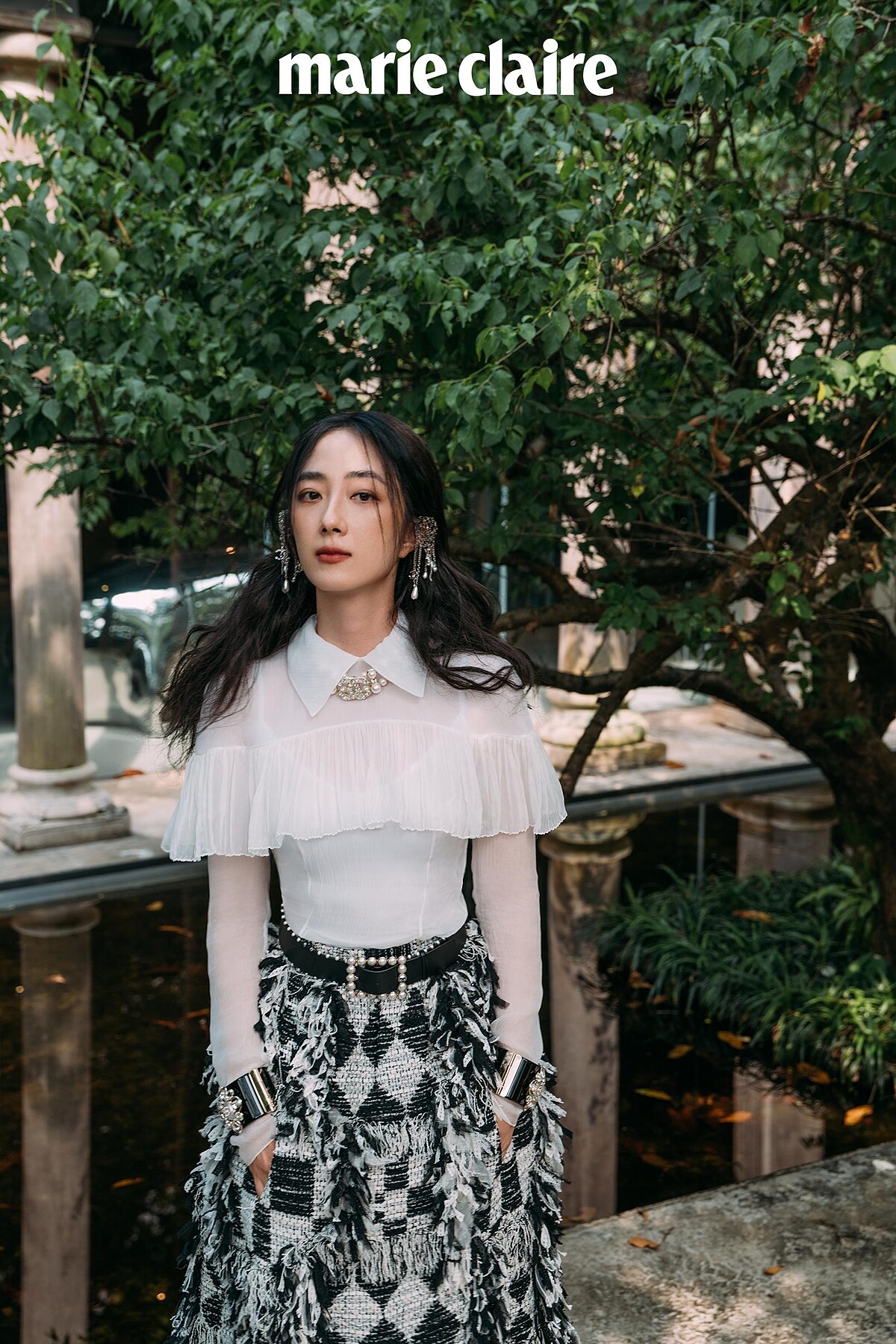 真絲綢紗襯衫飾以褶子荷葉邊與雙C水晶鑲飾鈕扣、黑白格紋斜紋軟呢流蘇長裙、銀色金屬垂墜式幻象珍珠流蘇耳扣、黑色皮革飾以幻象珍珠腰帶、黑色高級樹脂水晶鑲飾幻象珍珠手環、金屬水晶鑲飾雙 C Logo 造型飾以幻象珍珠頸鍊，all by CHANEL。