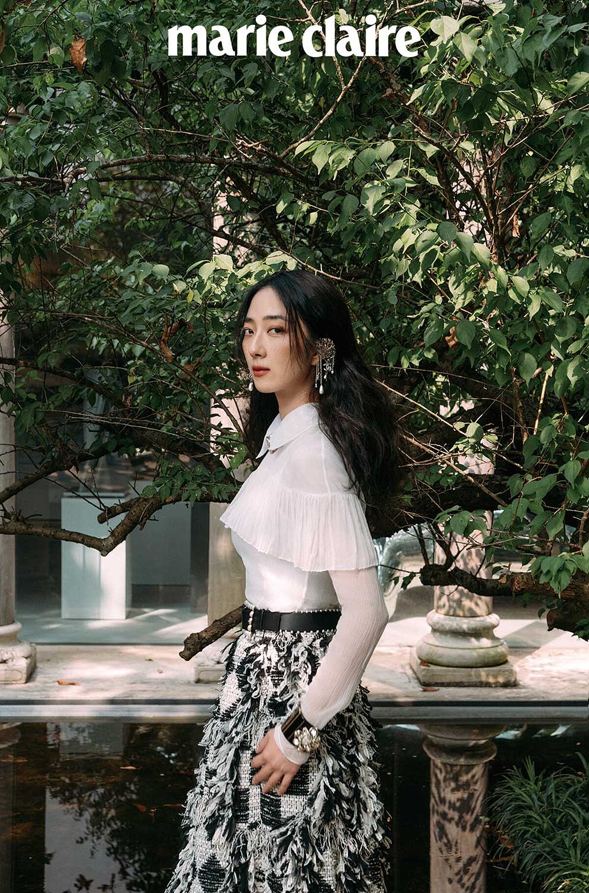 真絲綢紗襯衫飾以褶子荷葉邊與雙C水晶鑲飾鈕扣、黑白格紋斜紋軟呢流蘇長裙、銀色金屬垂墜式幻象珍珠流蘇耳扣、黑色皮革飾以幻象珍珠腰帶、黑色高級樹脂水晶鑲飾幻象珍珠手環、金屬水晶鑲飾雙 C Logo 造型飾以幻象珍珠頸鍊，all by CHANEL。