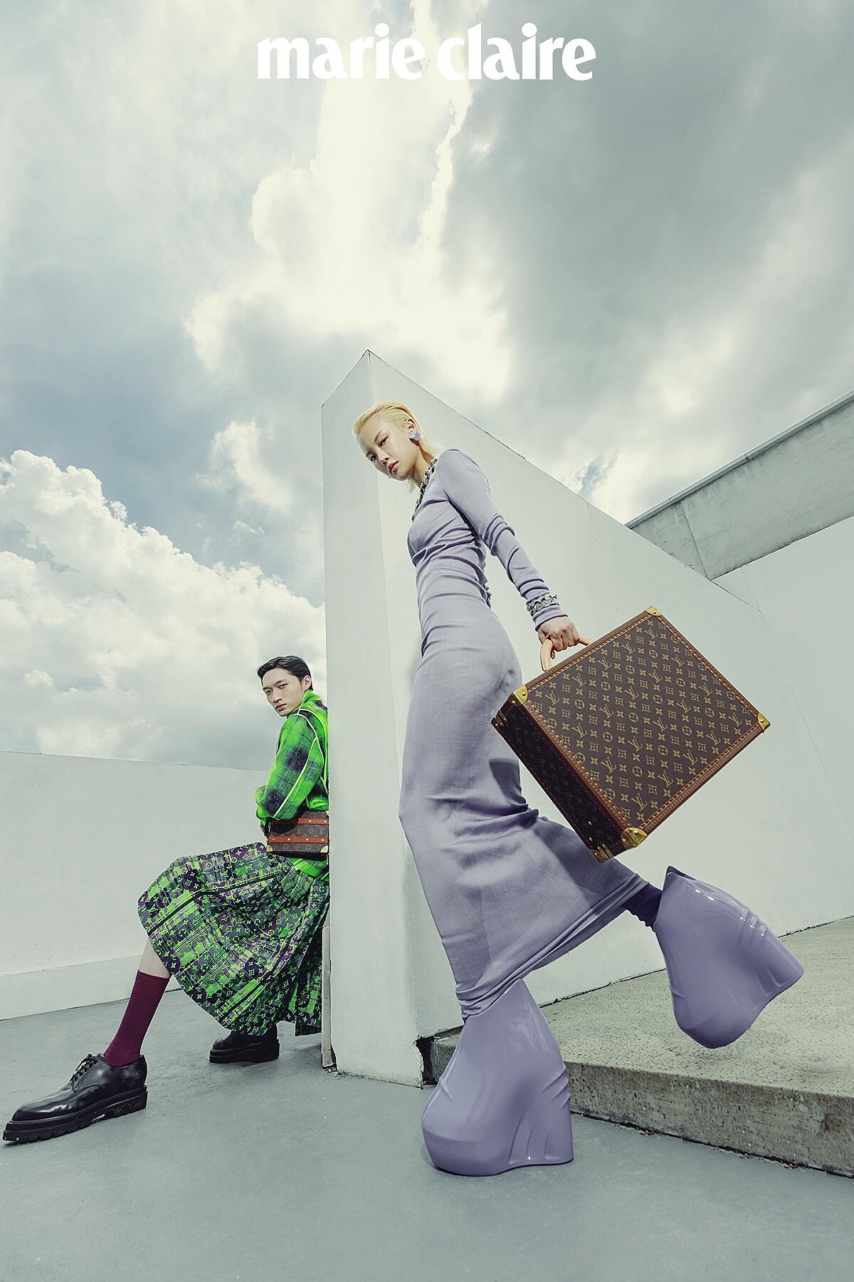 Gia Tang：紫色長洋裝、紫色耳環、金屬項鍊、金屬手環、紫色襪套式踝靴，all by Givenchy；Monogram 行李箱，Louis Vuitton。 Zachary Chou：螢光綠格紋外套、螢光綠 Monogram 裙裝，黑色 Monogram 皮鞋、Monogram 側背箱包，all by Louis Vuitton。