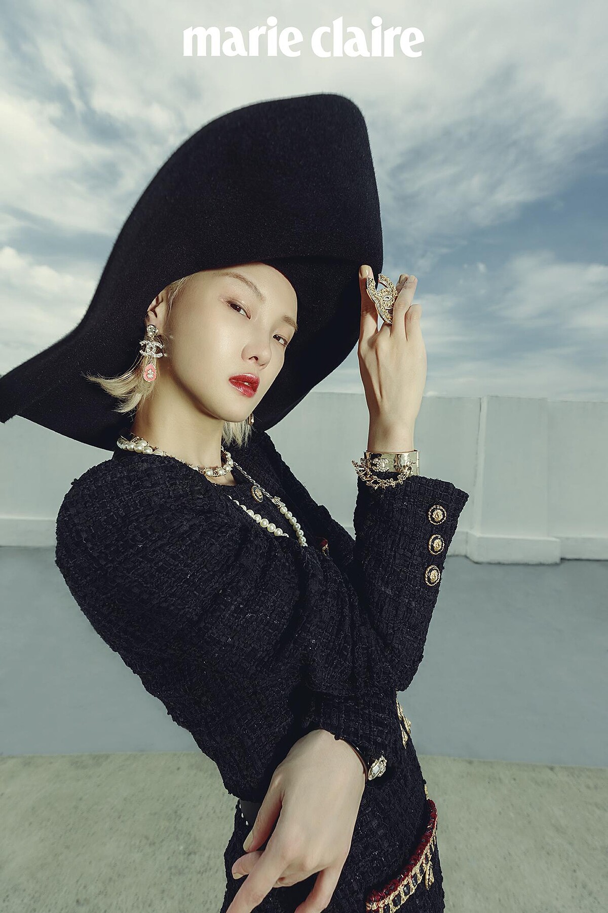 黑色寬沿帽、鑽飾耳環、珍珠短鍊、金屬珍珠項鍊、金屬鑽飾手環、黑色寬版手環、金色鑽飾胸針、黑色斜紋軟呢連身衣、珍珠皮帶，all by Chanel。