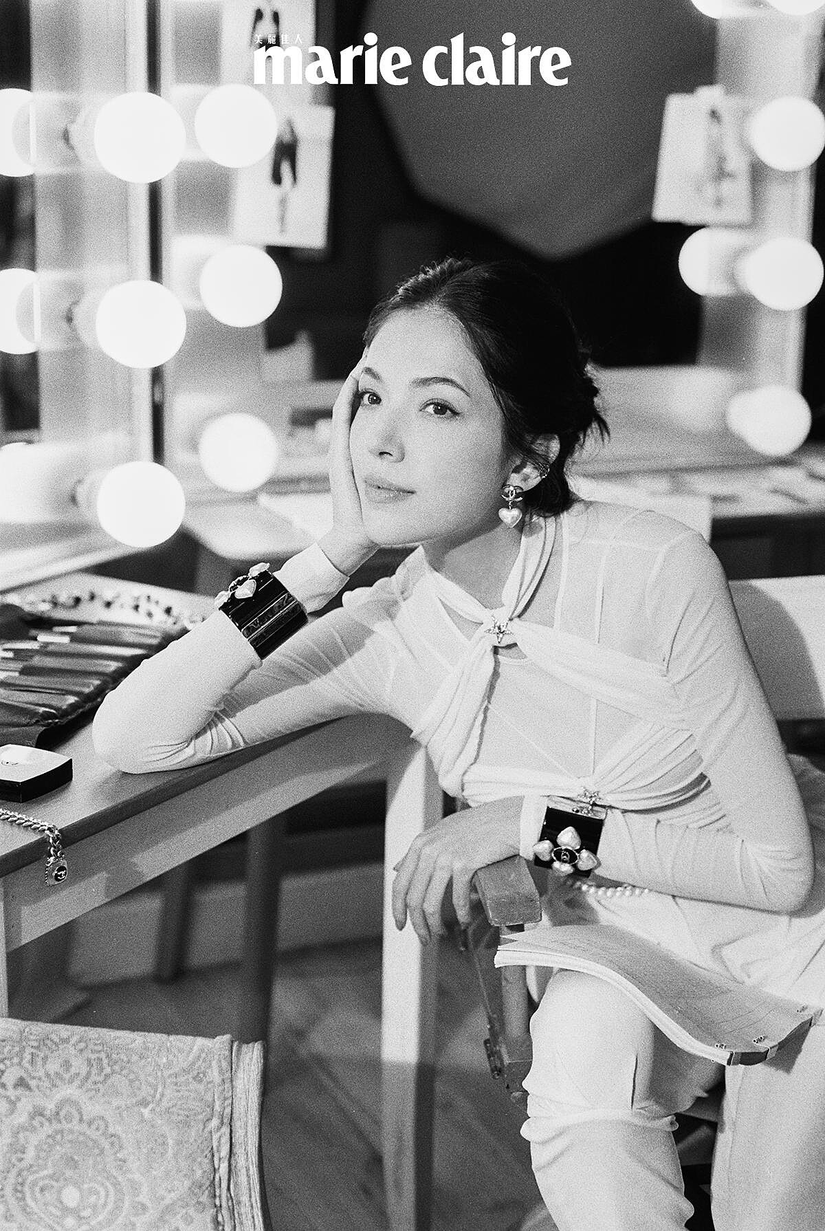 白色真絲縐紗綁帶造型上衣與同款長褲、 雙色皮革短靴、黑色高級樹脂馬爾他十字手環、金屬高級樹脂愛心造型耳環、金屬幻象珍珠腰鍊，all by CHANEL。