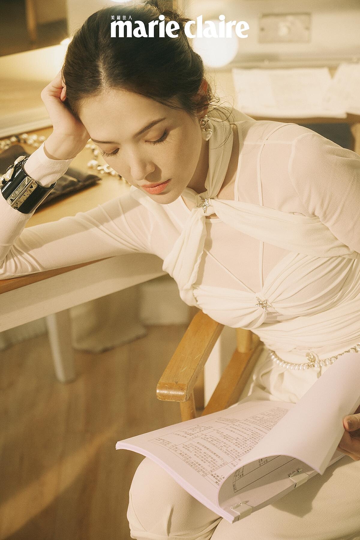 白色真絲縐紗綁帶造型上衣與同款長褲、 雙色皮革短靴、黑色高級樹脂馬爾他十字手環、金屬高級樹脂愛心造型耳環、金屬幻象珍珠腰鍊，all by CHANEL。