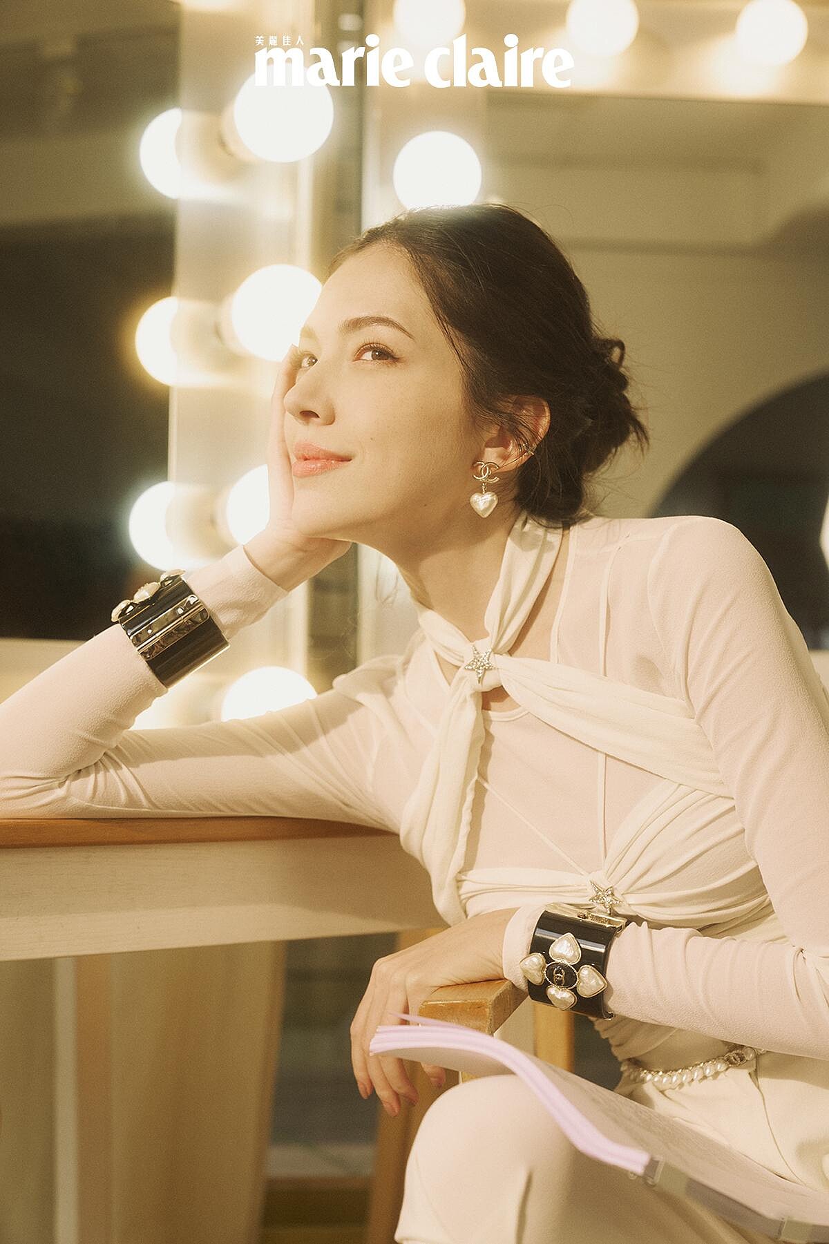 白色真絲縐紗綁帶造型上衣與同款長褲、 雙色皮革短靴、黑色高級樹脂馬爾他十字手環、金屬高級樹脂愛心造型耳環、金屬幻象珍珠腰鍊，all by CHANEL。