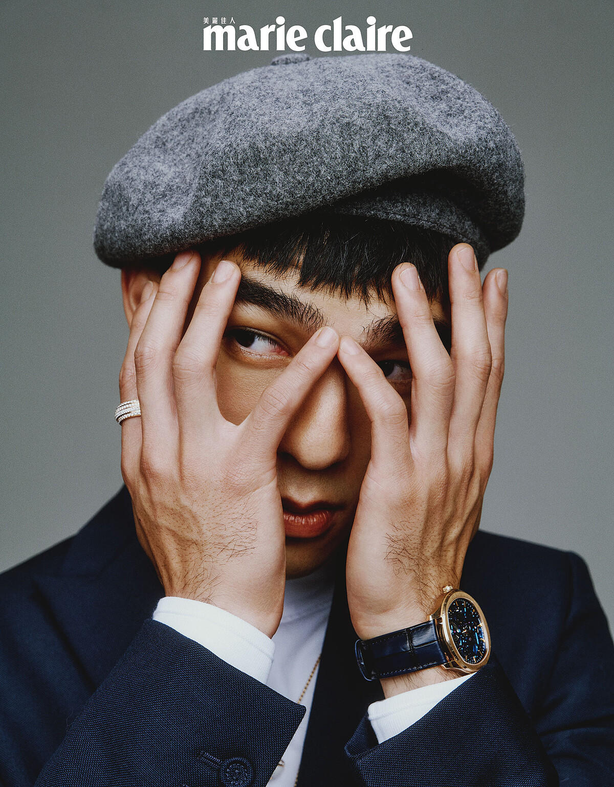 白色高領衫、深藍色附扣式腰帶西裝外套、寬版西裝褲，all by Dior Men；灰色蓓蕾帽，Kangol。Piaget Polo 系列18K玫瑰金鏤空機芯超薄腕錶、Piaget Possession 系列18K玫瑰金鑽石戒指、18K玫瑰金白玉髓鑽石墜鍊、18K白金鑽石墜鍊，all by Piaget。