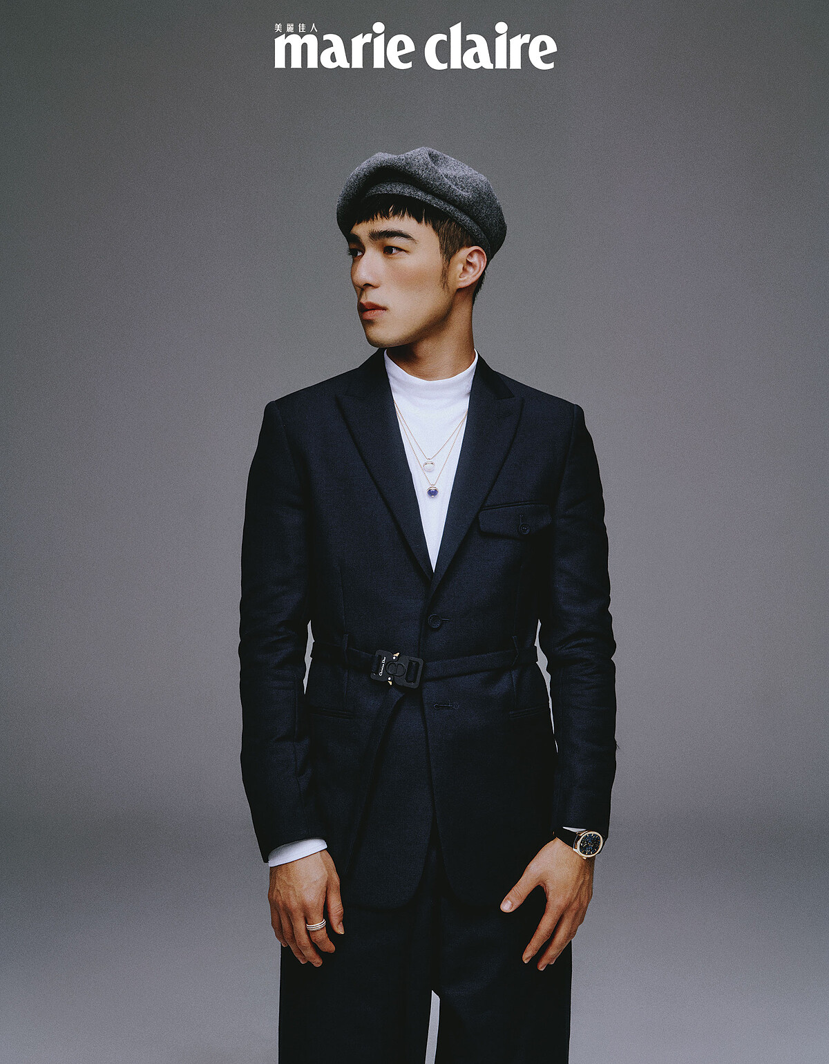 白色高領衫、深藍色附扣式腰帶西裝外套、寬版西裝褲，all by Dior Men；灰色蓓蕾帽，Kangol。Piaget Polo 系列18K玫瑰金鏤空機芯超薄腕錶、Piaget Possession 系列18K玫瑰金鑽石戒指、18K玫瑰金白玉髓鑽石墜鍊、18K白金鑽石墜鍊，all by Piaget。