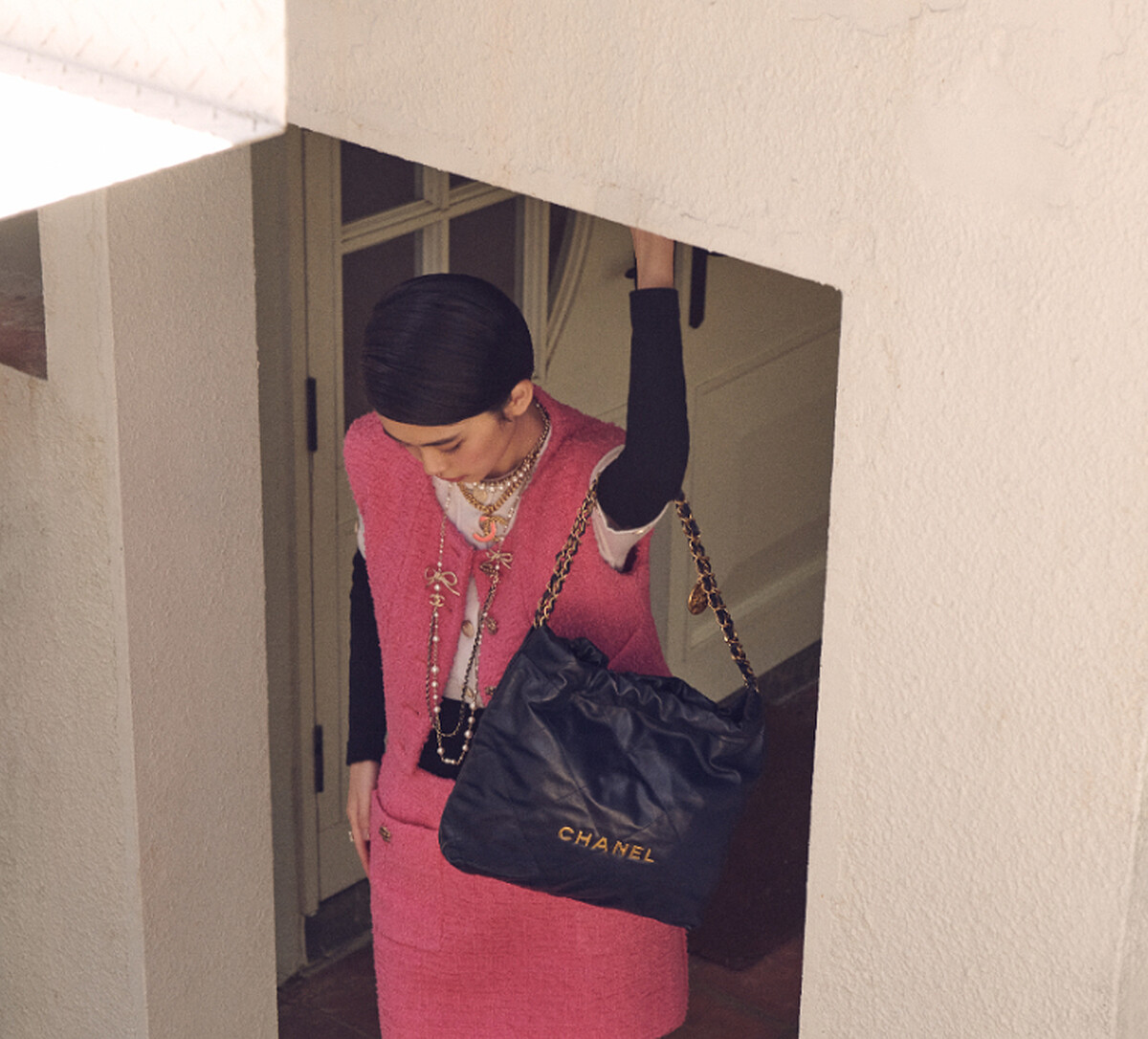 黑白拼接上衣、粉色斜紋軟呢背心、粉色斜紋軟呢半身裙、CHANEL 22包、服飾珠寶配件,All by CHANEL。