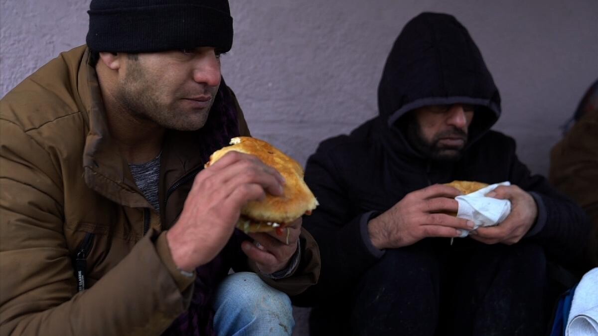 阿富汗難民青年，在路邊吃日本團隊購買救助的雞肉漢堡