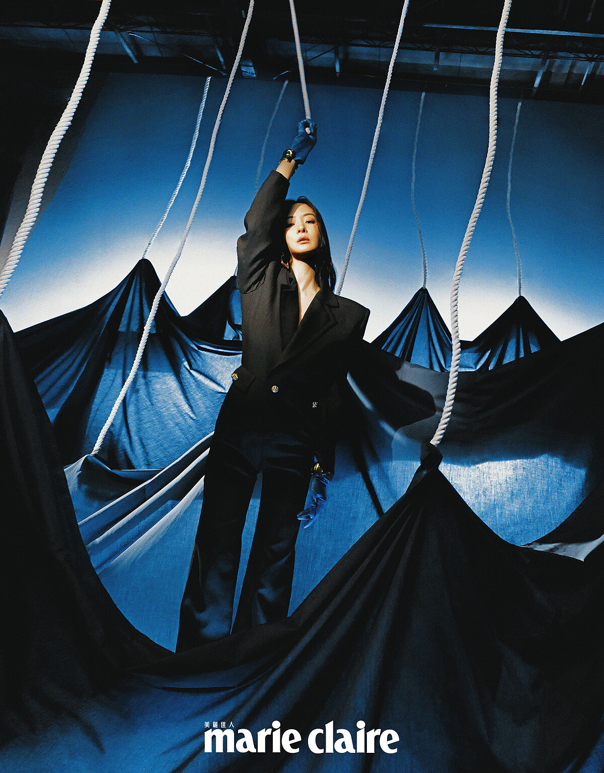 黑色西裝連身服、藍色皮質手套、金色手環，all by Saint Laurent。