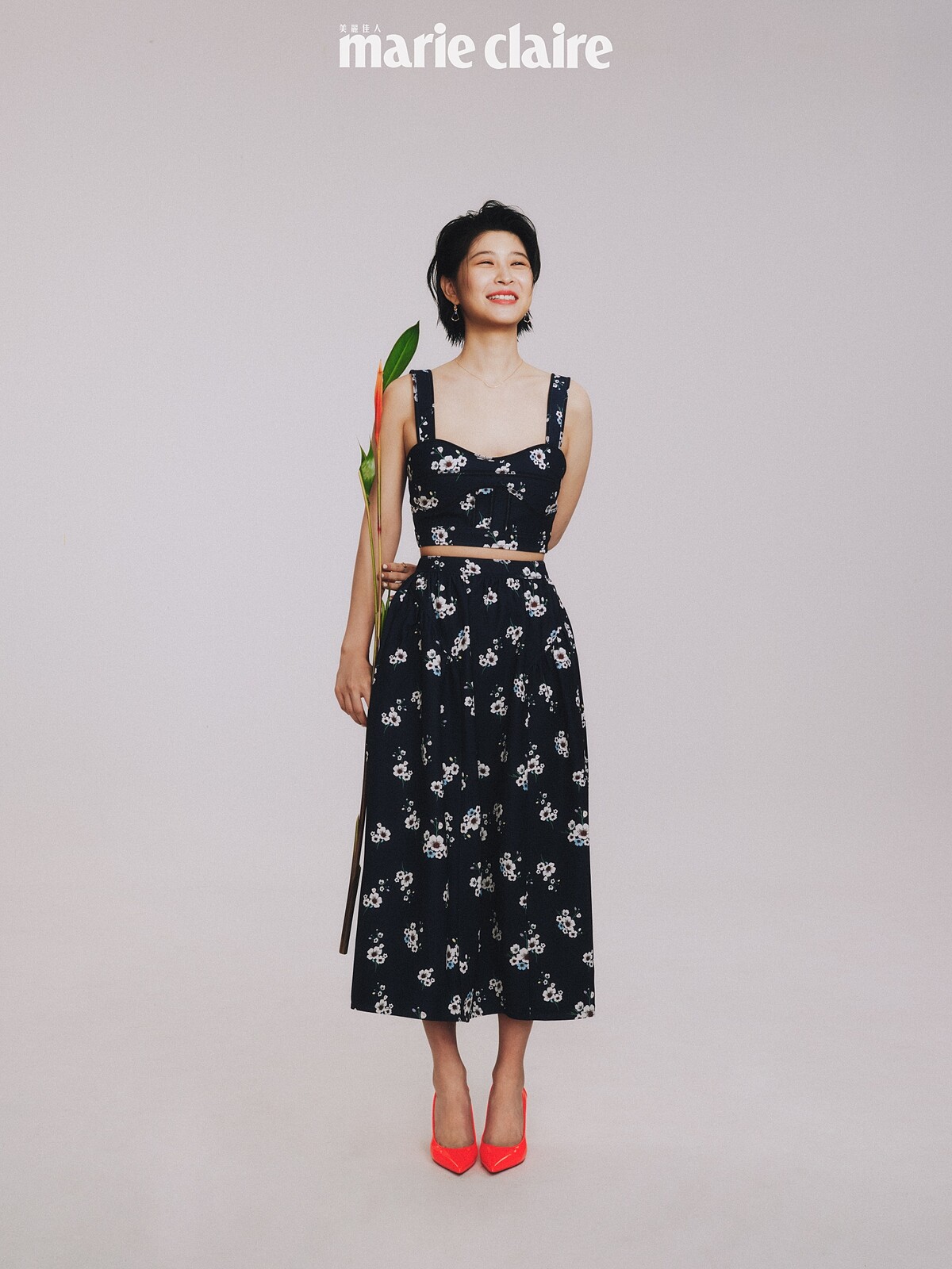 花卉圖案短版上衣、長裙，both by Self-Portrait；三件式組合垂墜耳環、項鍊，both by agete；橘紅色高跟鞋，Christian Louboutin。