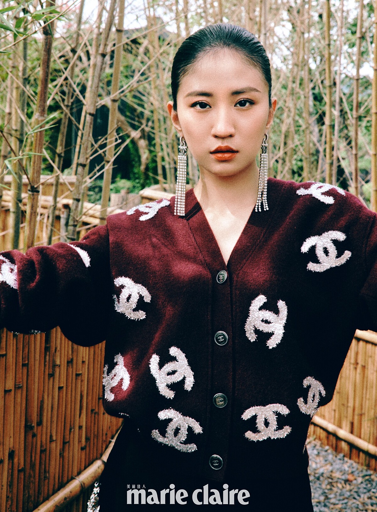 酒紅色刺繡圖紋針織衫、黑色長裙、長耳環、手環，all by Chanel。