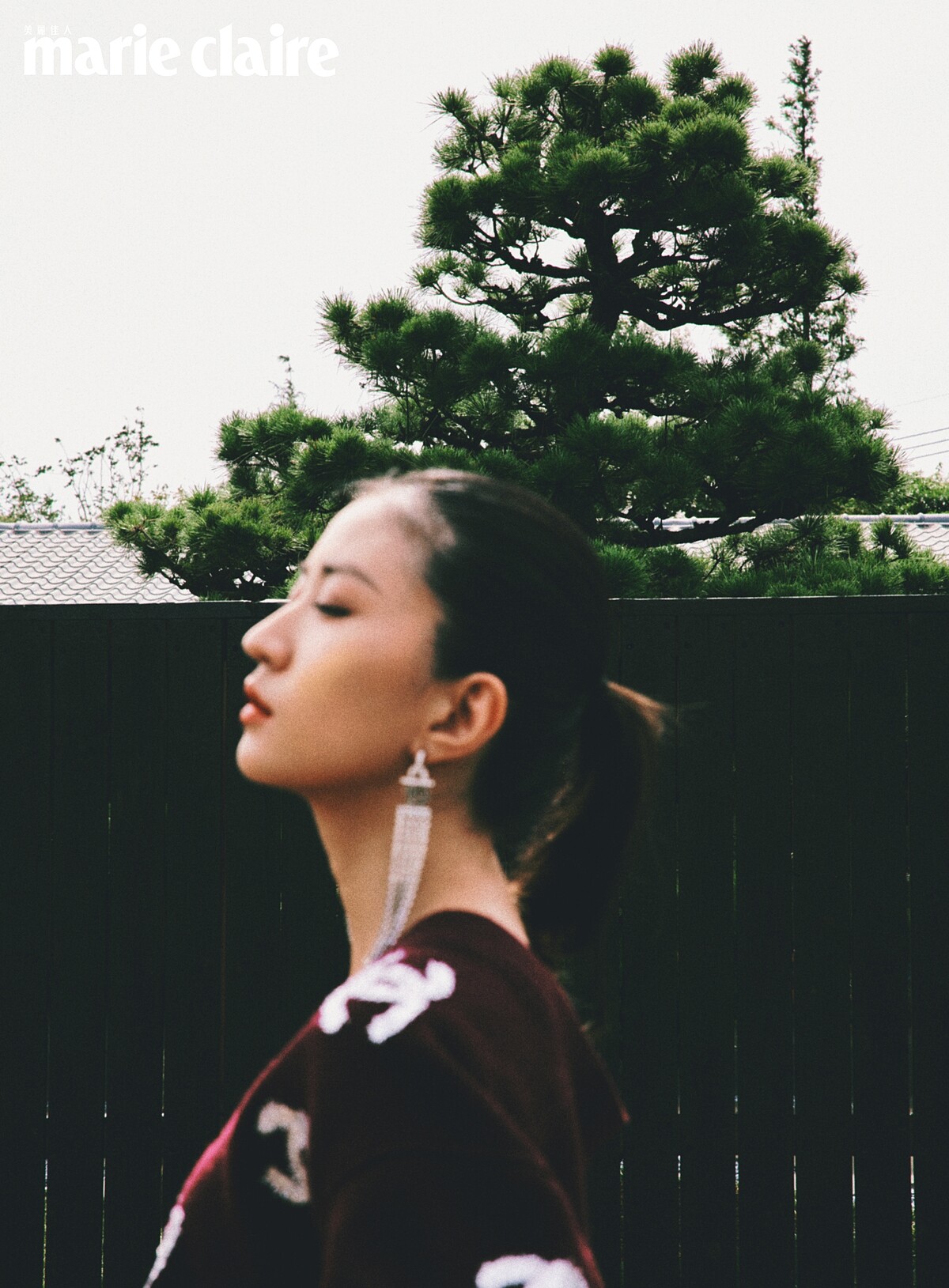 酒紅色刺繡圖紋針織衫、黑色長裙、長耳環，all by Chanel。