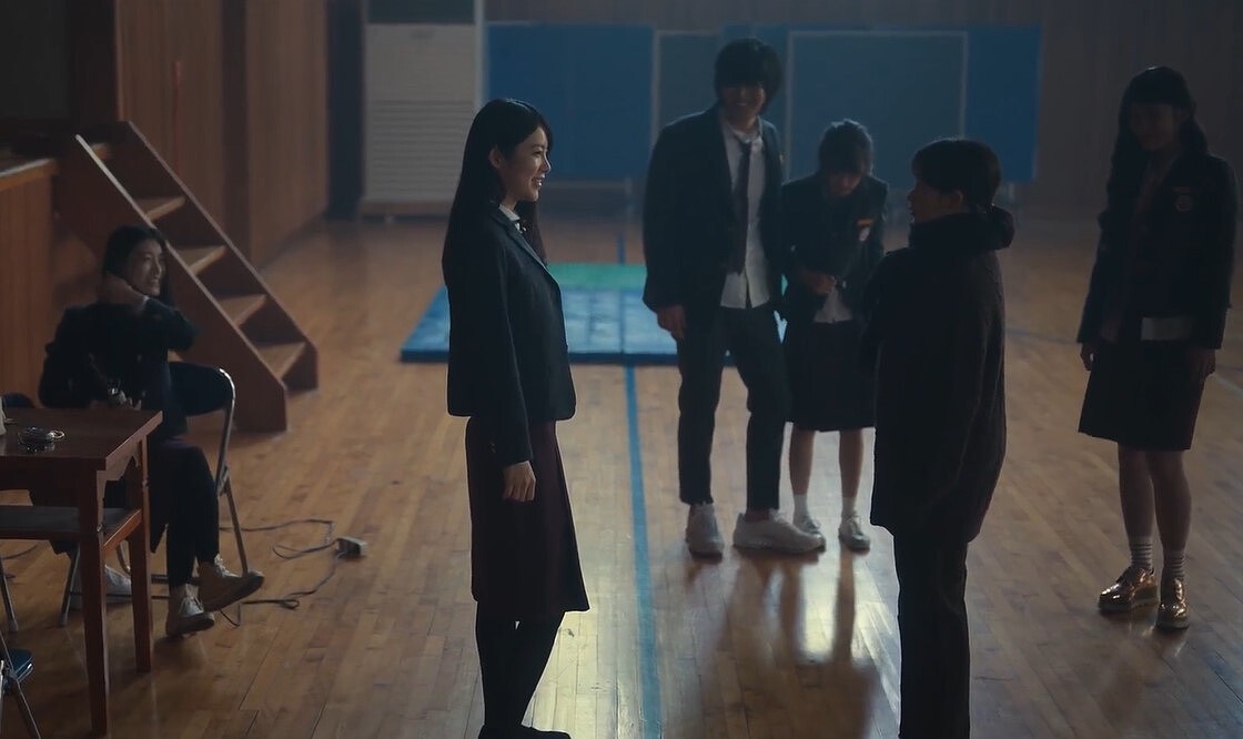 《黑暗榮耀》高中時代的朴涎鎮和李沙拉(左一左二)，和體育館地板上分界線另一端的下流同學崔惠程、孫慏梧，清楚區隔彼此的位階