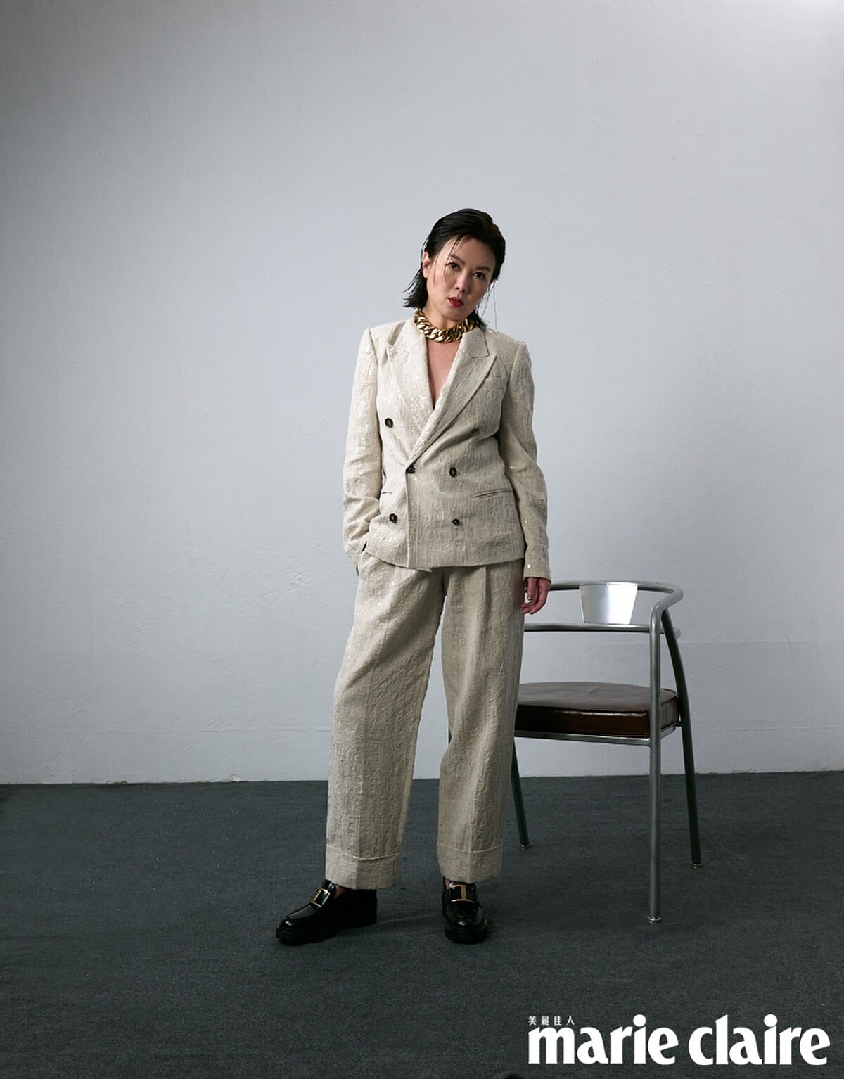 米色西裝外套、黑色內搭背心、米色西裝長褲，all by Brunello Cucinelli；黑色皮革樂福鞋，Tod&rsquo;s；金色項鍊，Recovery。