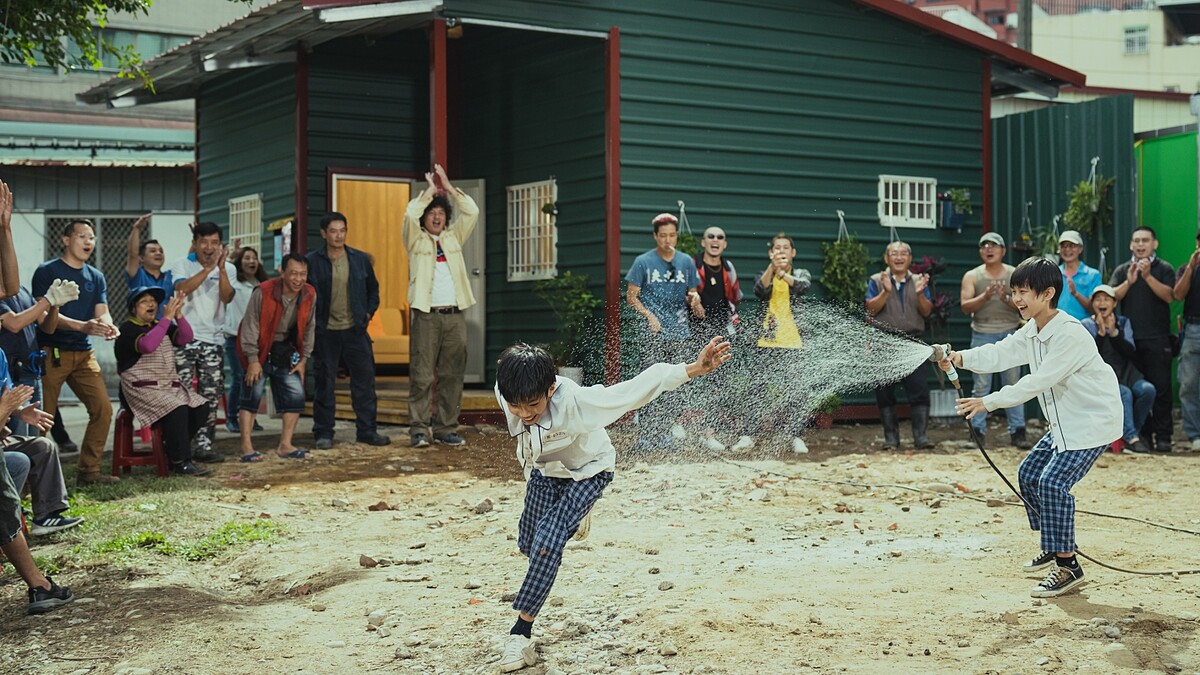 《做工的人 電影版》蓋好新的鐵皮屋之後,眾人在屋外歡樂打水仗,圖為唐浩哲與楊學湧兩位小童星。