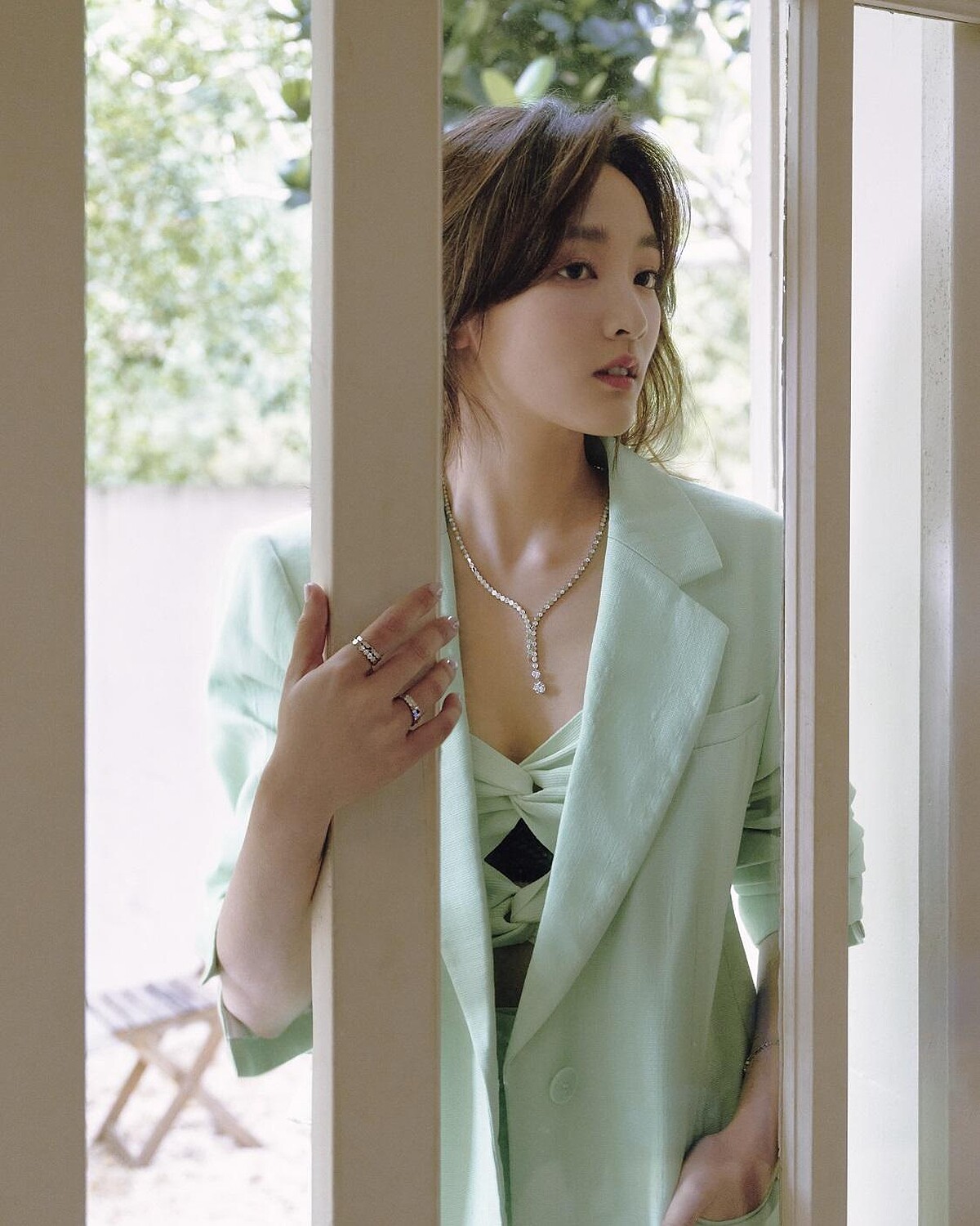 Bee My Love 18K白金項鏈,鑲嵌2顆 Taille Impératrice 皇后式切割鑽石,約重1.5克拉及0.5克拉,以及明亮式切割鑽石、Bee My Love 18K白金半鋪鑲明亮式切割鑽石戒指、Bee My Love 18K白金鑲嵌明亮式切割鑽石戒指、Bee My Love 18K白金戒指,all by Chaumet。 綠色扭結背心、西裝外套、亞麻短褲,all by Sandro。