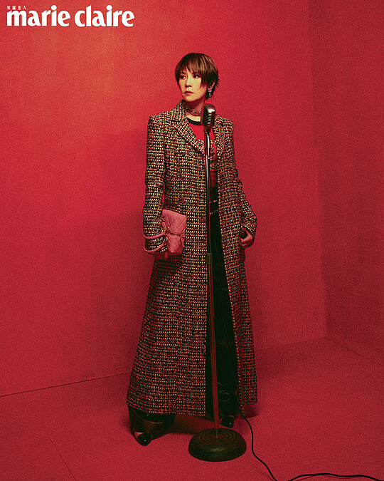 斜紋軟呢長版大衣、Logo 長袖上衣、酒紅色皮革長褲、吊墜耳環、金色 Logo 頸鍊、橘色串珠腰鍊、黃黑雙色皮革高跟鞋，all by CHANEL。