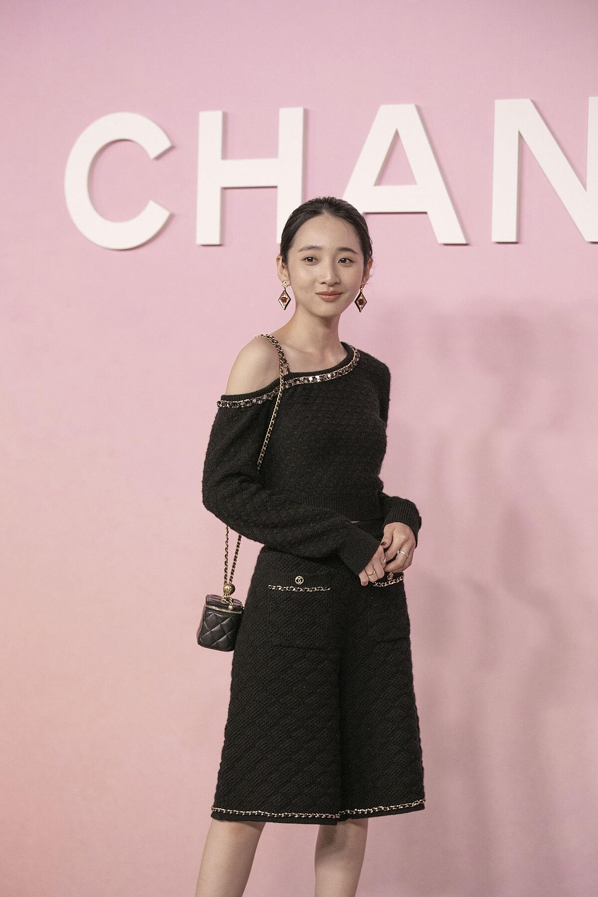 李沐穿著香奈兒2023/24秋冬前導系列黑色皮穿鍊滾邊斜肩上衣、百慕達短褲、配戴香奈兒高級珠寶。