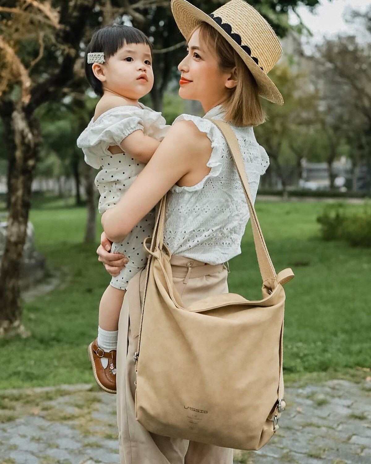 Keira凱拉以純色質感皮革2WAY媽媽包搭配同色系草帽、卡其西裝褲，展現簡約時髦的日常造型。