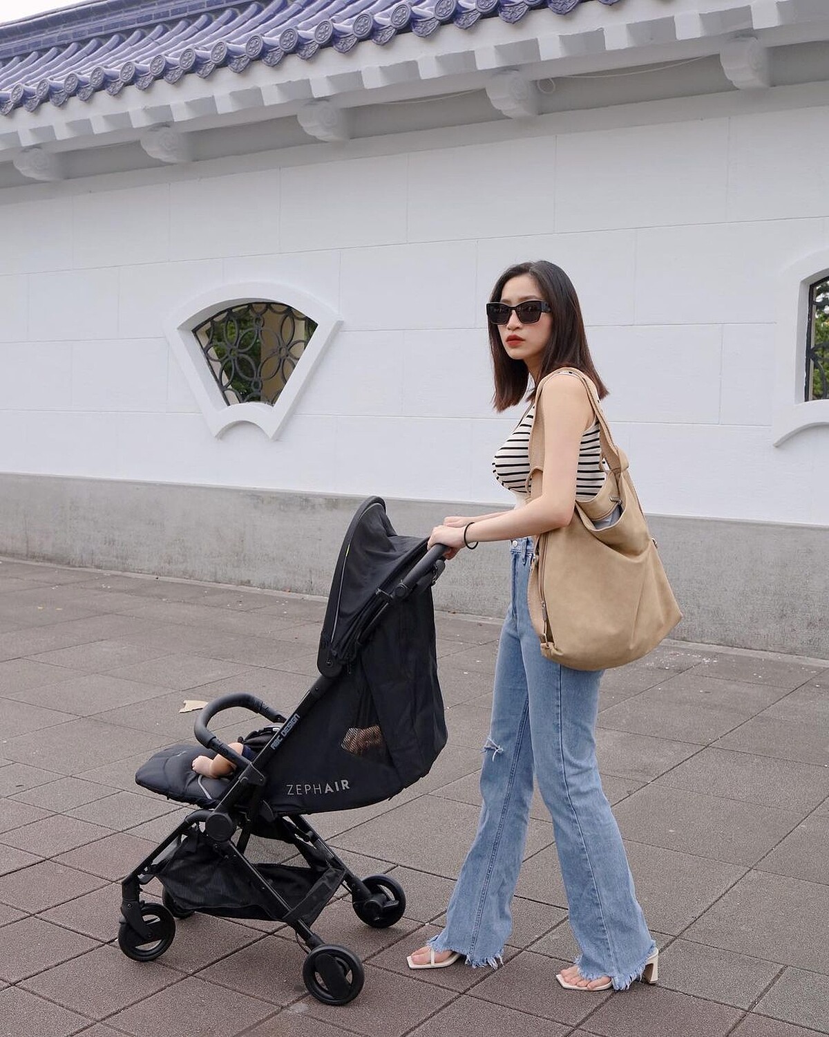 凌而則是以充滿法式風格的橫條紋背心搭配丹寧長褲，再背上純色質感皮革2WAY媽媽包搭配出優雅率性。