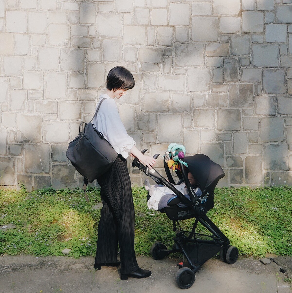 Hannah喜愛碳灰黑純色質感皮革後背媽媽包，可以方便掛在推車上，皮革質感的簡約設計能夠兼顧質感穿搭。