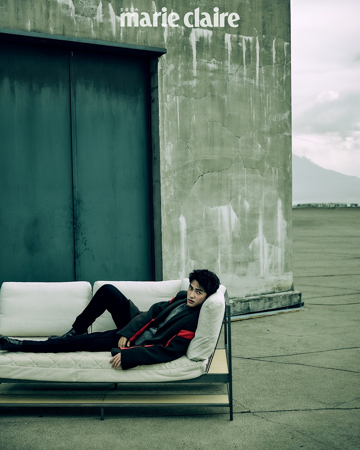 咖啡色拼接西裝外套、灰色針織衫、黑色西裝褲、黑色襪子，all by Prada；黑色皮靴，Christian Louboutin。