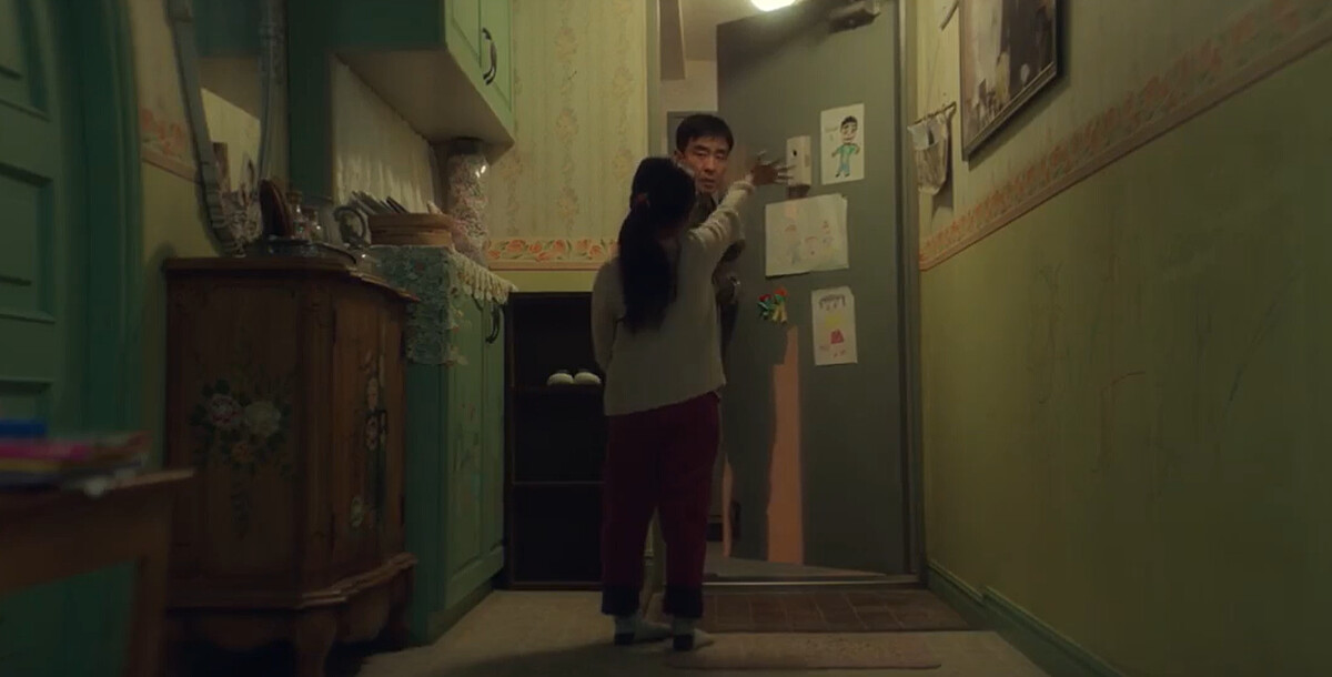 喜秀(背對者)像媽媽一樣,搖搖手點亮感應燈,再目送張洙源出門上班,張洙源說再見久久無法闔上門