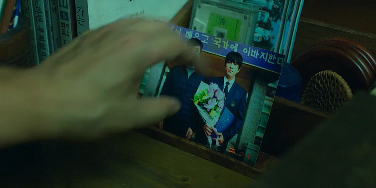 全永錫在陌生人出現時,警覺地把和兒子的合照蓋上