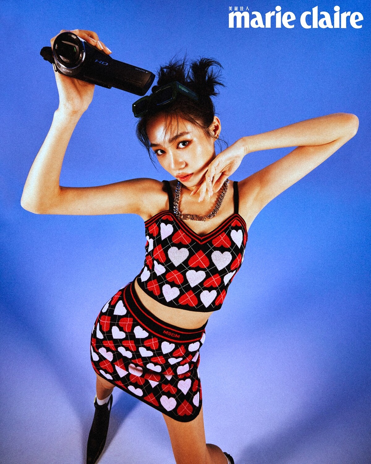 愛心印花背心、愛心印花短裙，both by MSGM；黑色金釦踝靴，Jimmy Choo；綠色窄版墨鏡、金屬項鍊，both by Off-White。