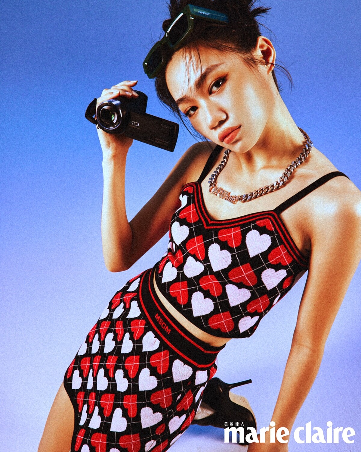 愛心印花背心、愛心印花短裙，both by MSGM；黑色金釦踝靴，Jimmy Choo；綠色窄版墨鏡、金屬項鍊，both by Off-White。