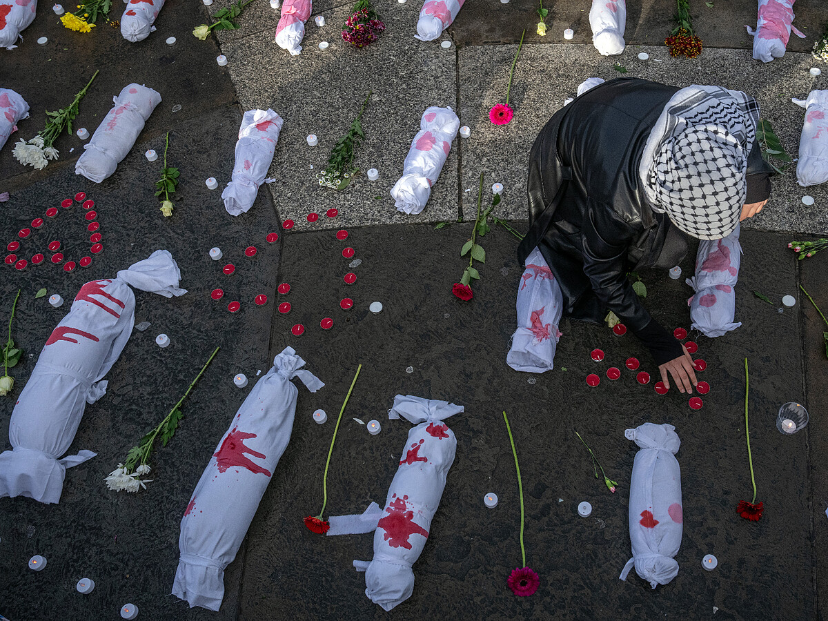 英國倫敦，一場呼籲哈馬斯和以色列停火的抗議活動中，一名女性在代表死嬰的小包束中整理蠟燭。