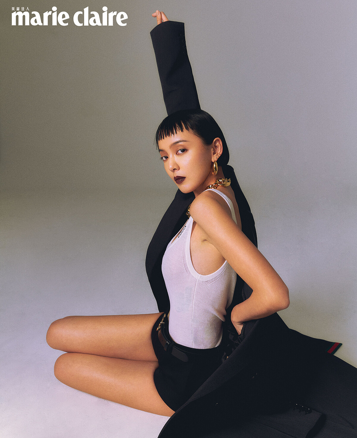 中灰混羊毛長外套、白色羊絨真絲背心、黑色低腰羊毛短褲、Marina Chain 項鍊、Marina Chain 耳環，all by Gucci。