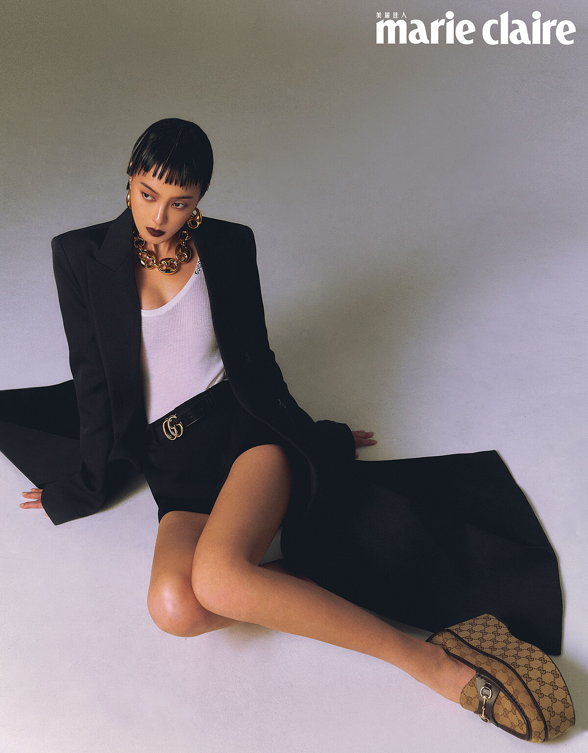 中灰混羊毛長外套、白色羊絨真絲背心、黑色低腰羊毛短褲、Marina Chain 項鍊、Marina Chain 耳環、Horsebit GG厚底鞋，all by Gucci。