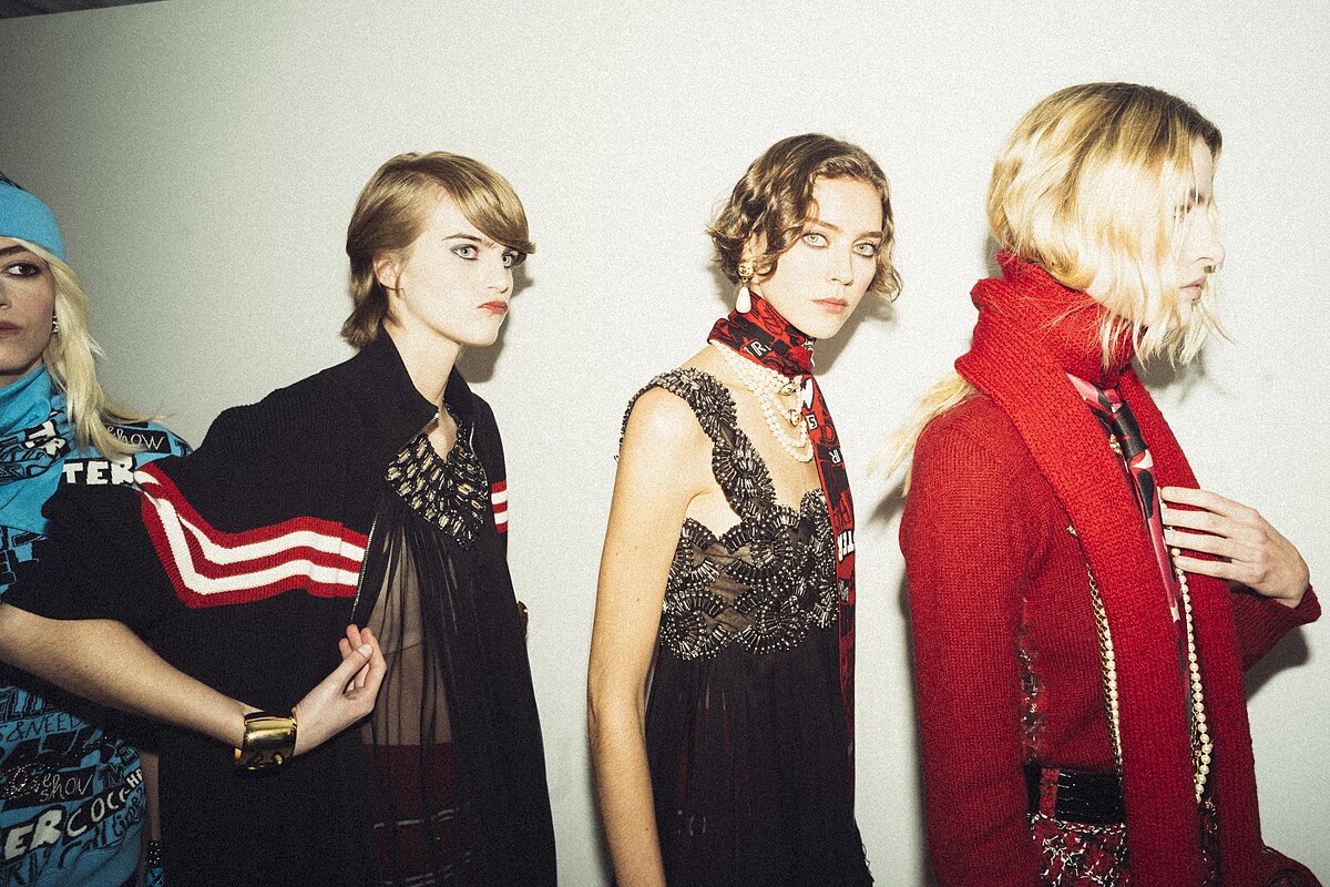 服裝秀開始前幾分鐘，三位精神集中的模特兒。中間是這系列的代表作，一件由 Lemari&eacute; 工坊製作的連身裙：在黑色絲綢薄紗上，用一千個安全別針縫製出22個 Chanel Logo。