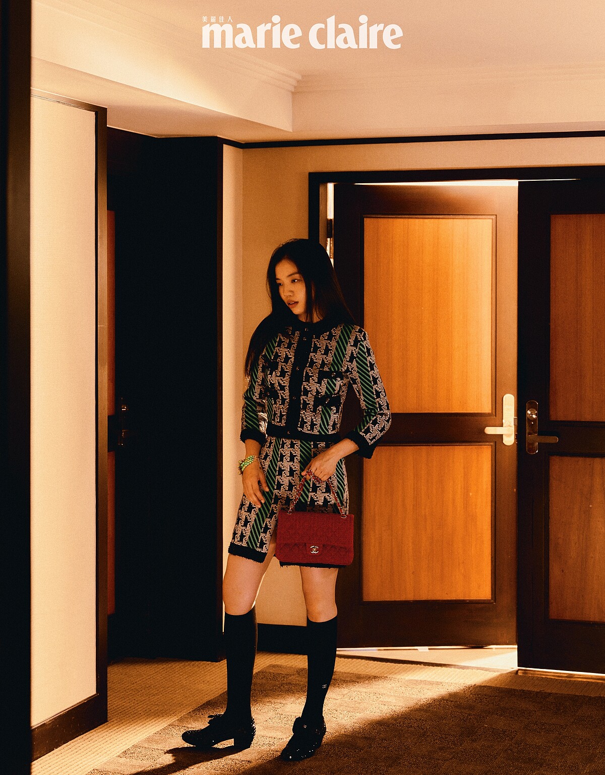 綠色千鳥格紋針織衫、綠色千鳥格紋短裙、綠色花朵手環、黑色長襪、黑色蝴蝶結瑪莉珍鞋、紅色斜紋軟呢肩背包，all by CHANEL。