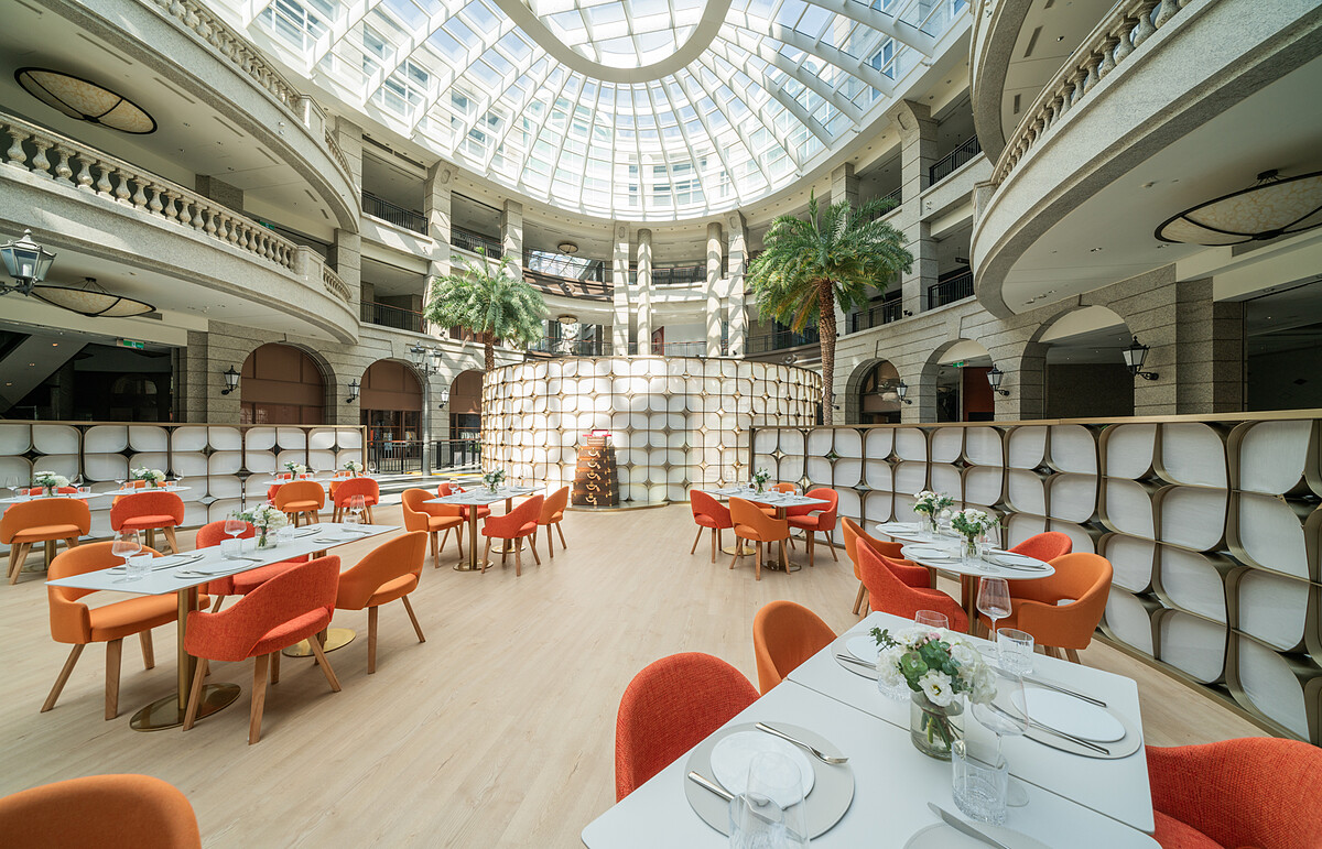 Caf&eacute;坐落於寶麗廣塲的中庭，設計靈感來自金色花瓣，環境溫暖木質調，並以路易威登經典硬箱裝飾，完美詮釋法式生活藝術（Art de Vivre）的真諦。