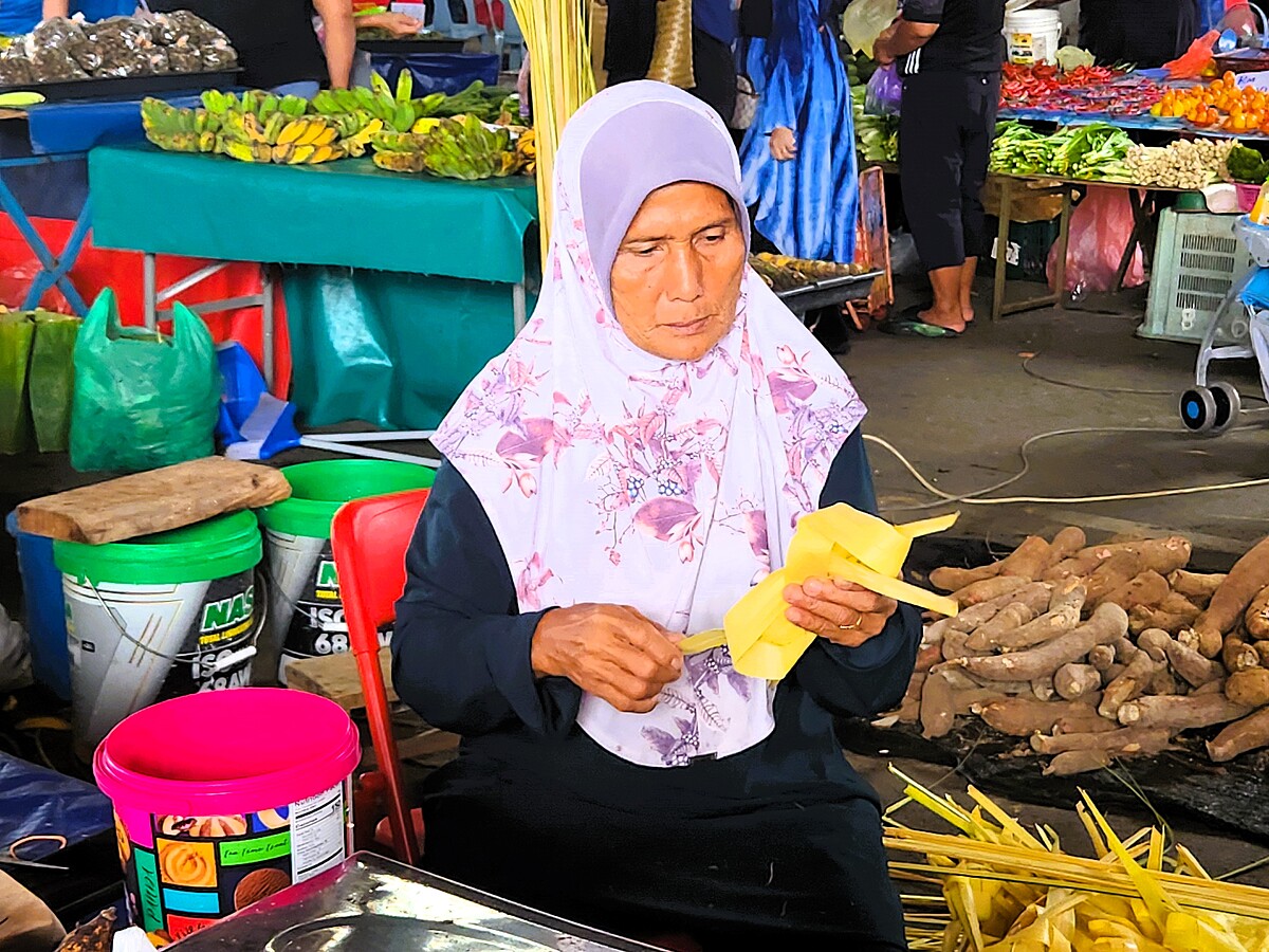 婦人於週日市集中製作手工藝品