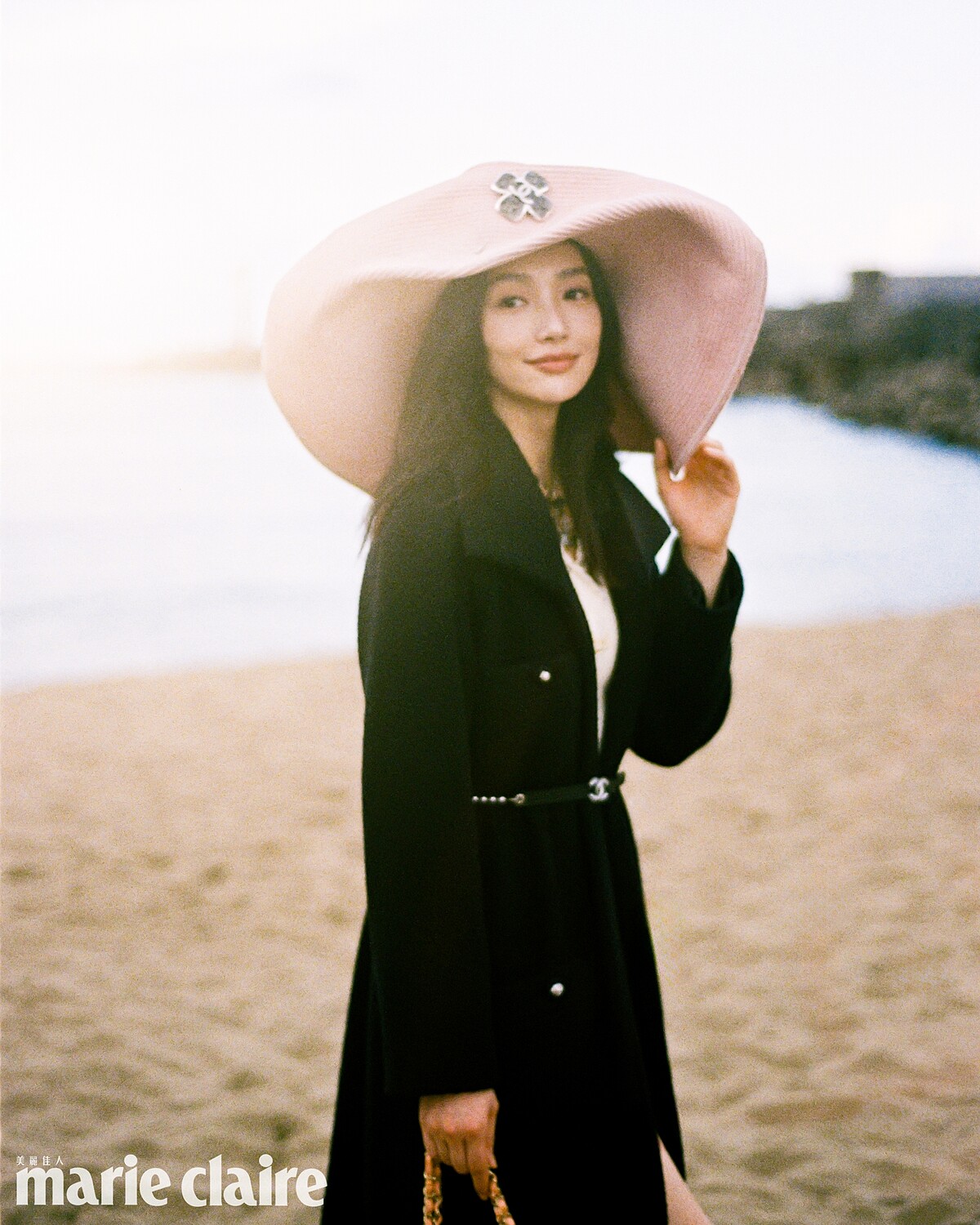 （Cecilia Choi）黑色斜紋軟呢長版綁帶大衣、白色針織洋裝、粉色寬沿草帽、皮穿鍊腰鍊、橘色皮革菱紋口蓋包，all by Chanel。