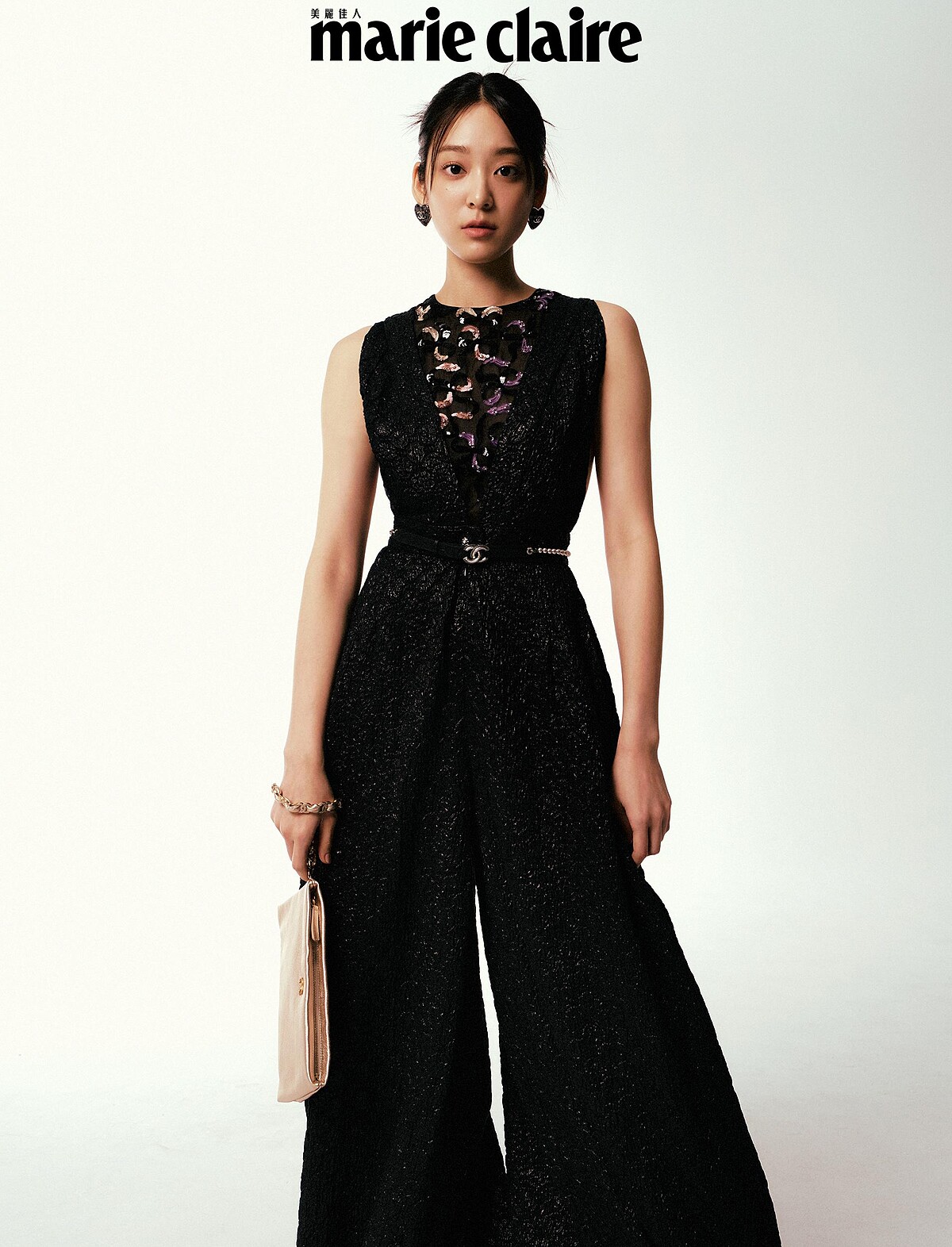 黑色刺繡背心、黑色連身褲、珍珠腰帶、心型耳環、金色手拿包，all by CHANEL。